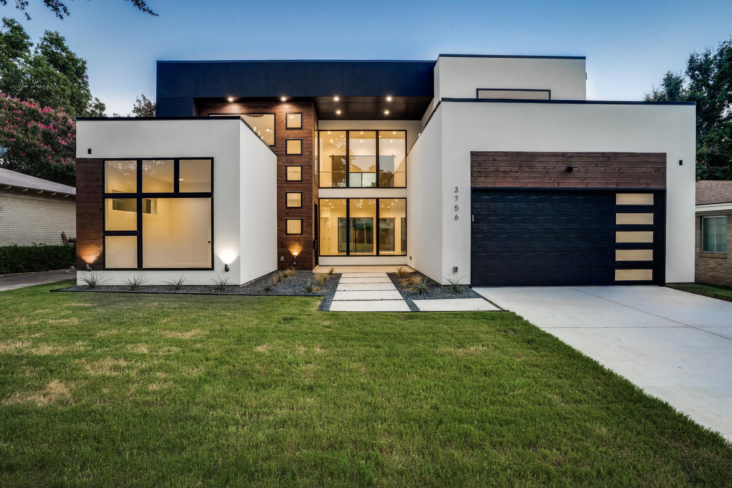Modern new construction custom home with white stucco facade, wood accents, and contemporary flat roof design at twilight in University Park, Texas