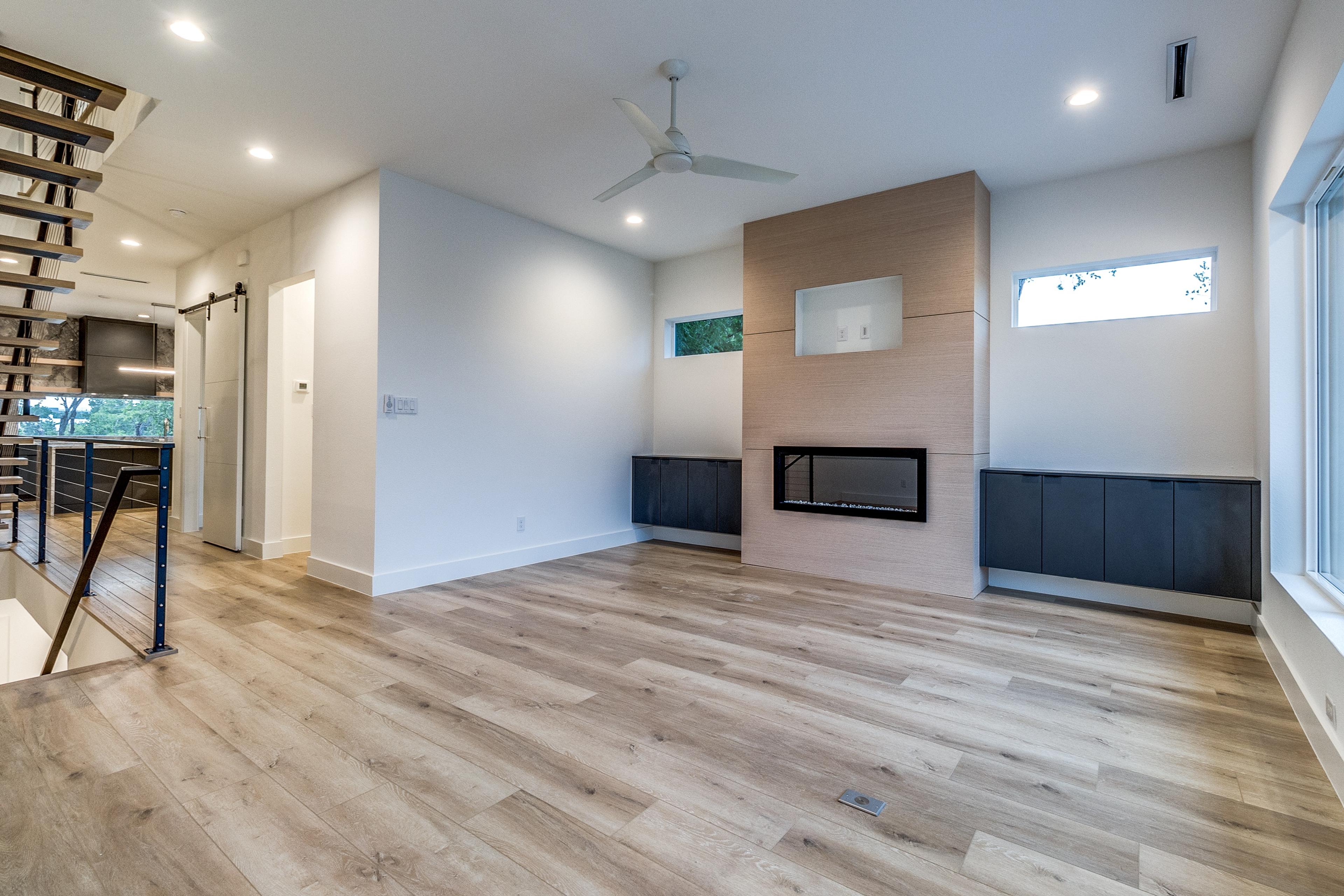 Empty modern living room with linear fireplace and light wood floors before virtual staging in Dallas, Texas