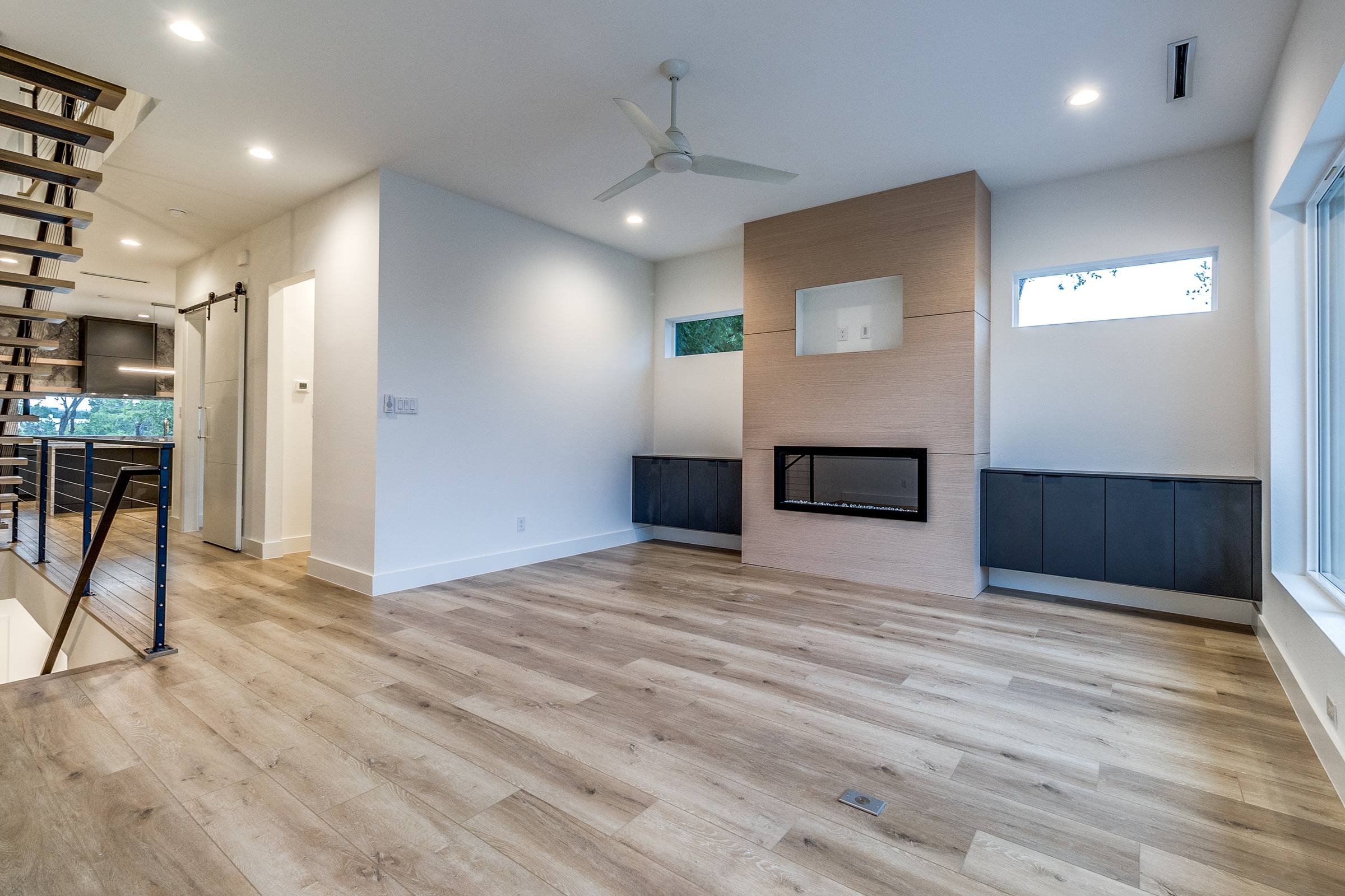 Empty modern living room with linear fireplace and light wood floors before virtual staging in Dallas, Texas
