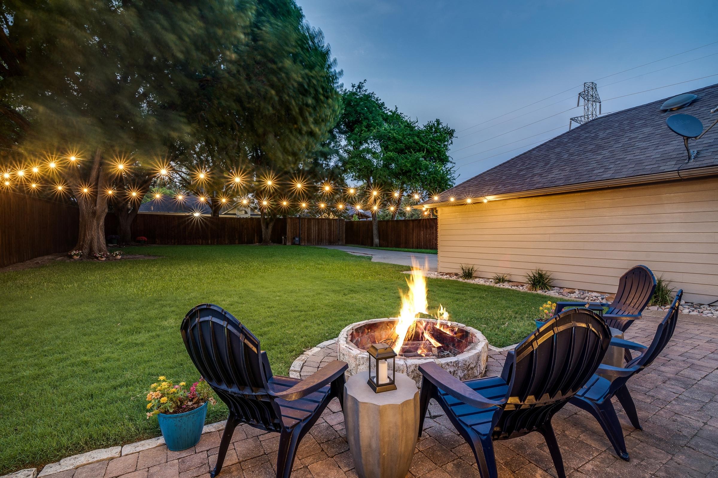 Backyard fire pit with Adirondack chairs and string lights at twilight in Richardson, Texas