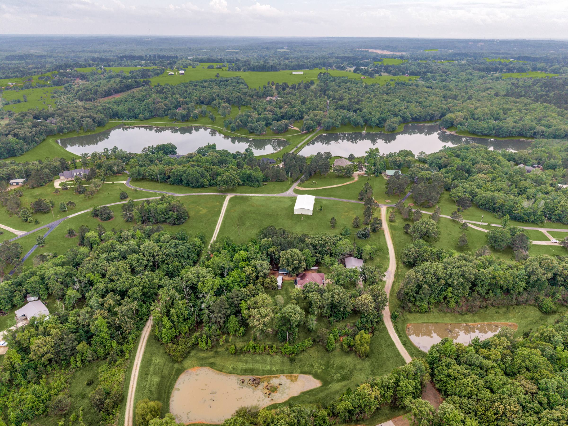 Wide aerial of a rural Lindale, TX lakefront property with lush greened lawns and vibrant tree canopy after Shoot2Sell Aerial Green Grass correction.