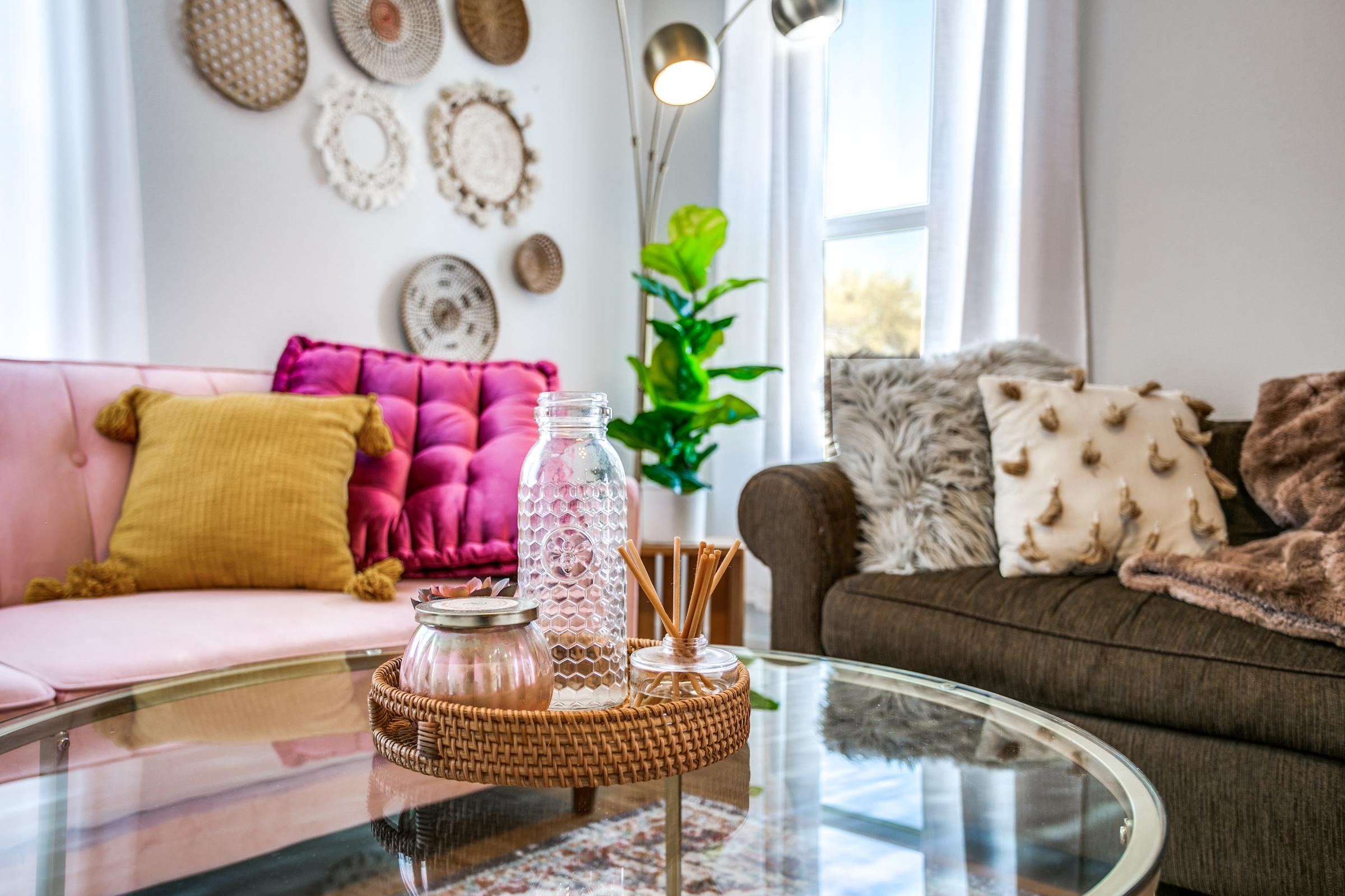Cozy eclectic living room with pink and brown sofas, boho wall decor, and glass coffee table in a Fort Worth, Texas vacation rental