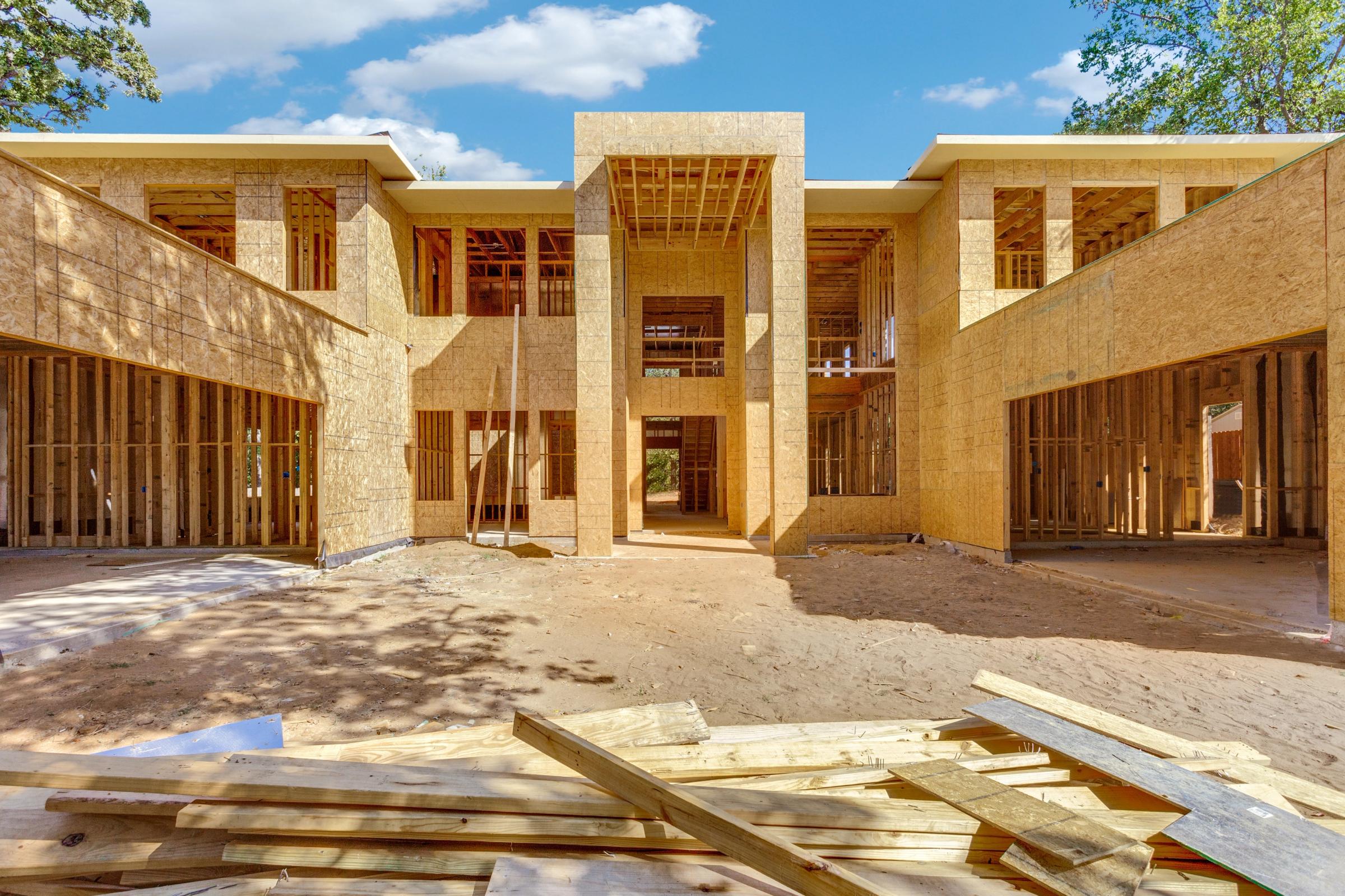 Large luxury home under construction showing wood framing stage with two-story entry in Southlake, Texas