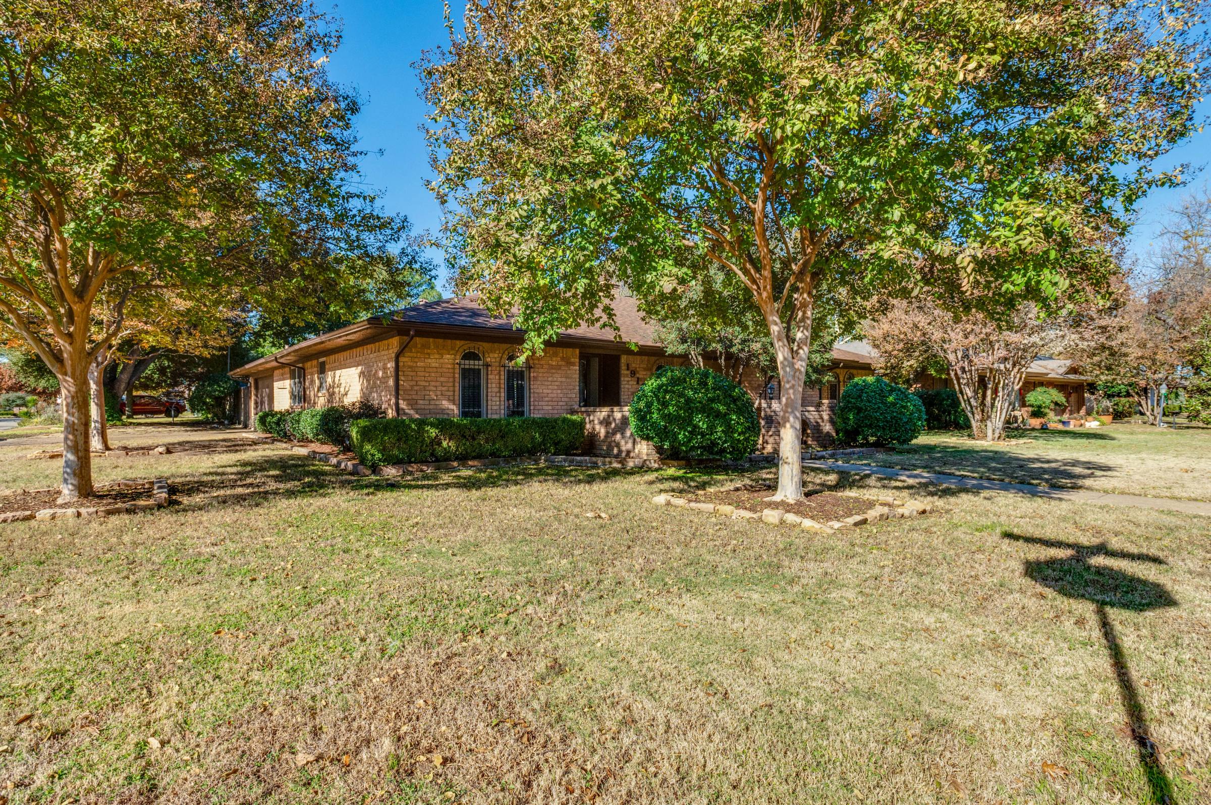 Single-story brick ranch home in Arlington with patchy brown front lawn before green grass photo enhancement