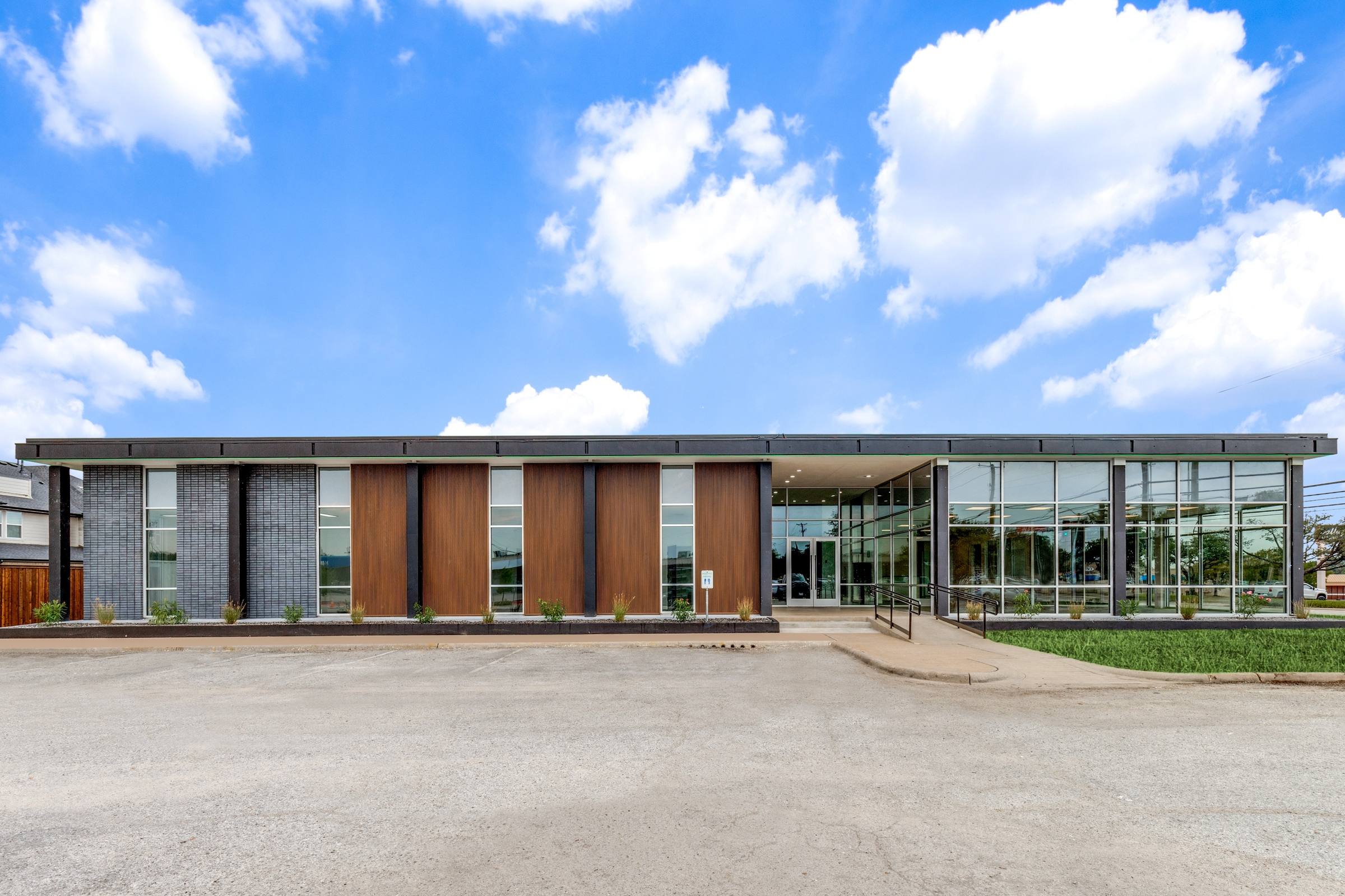 Modern commercial building exterior with concrete parking lot before virtual staging enhancement in Farmers Branch, Texas