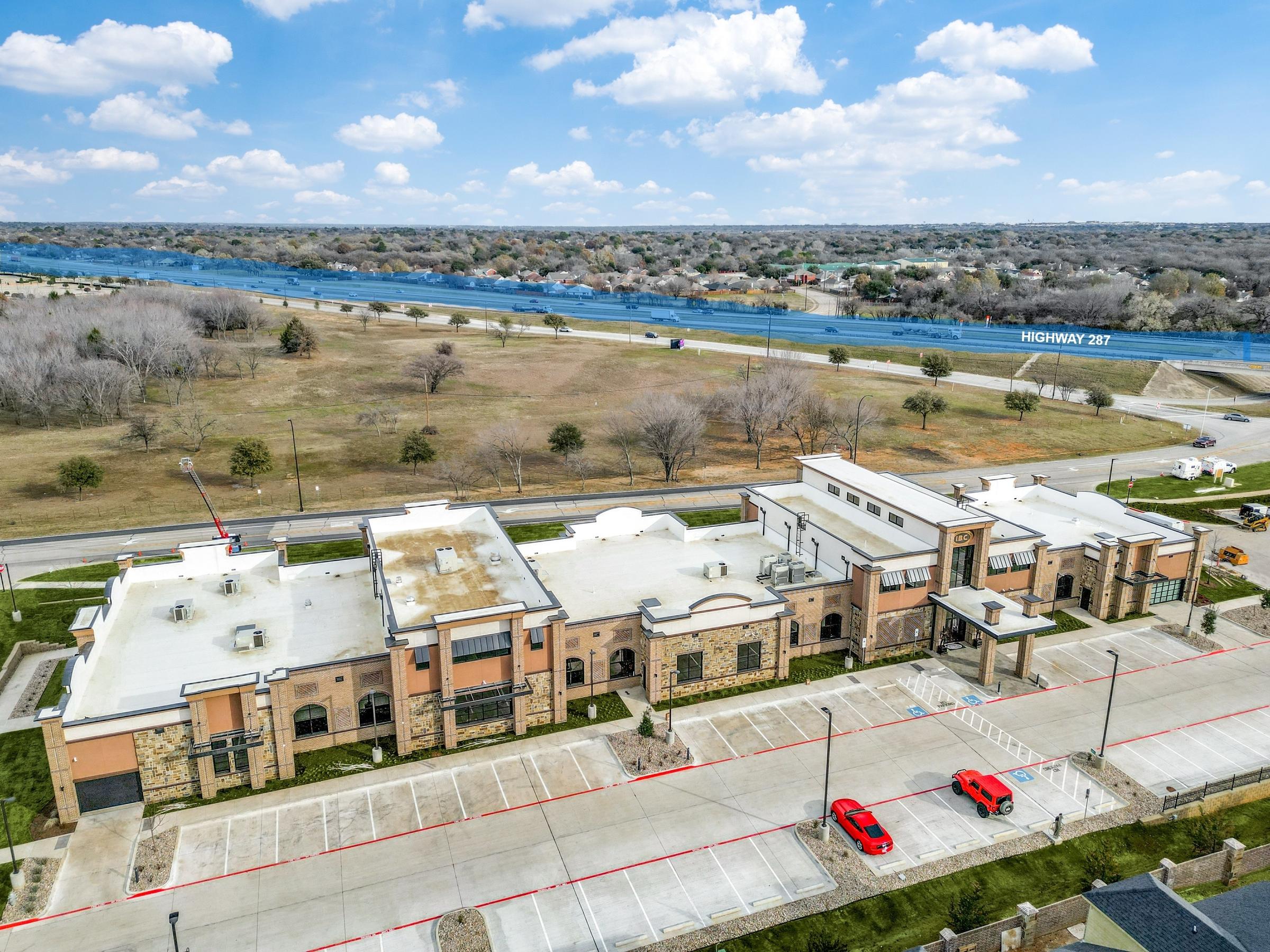 Aerial view of stone and brick commercial building with highway access in Arlington, Texas
