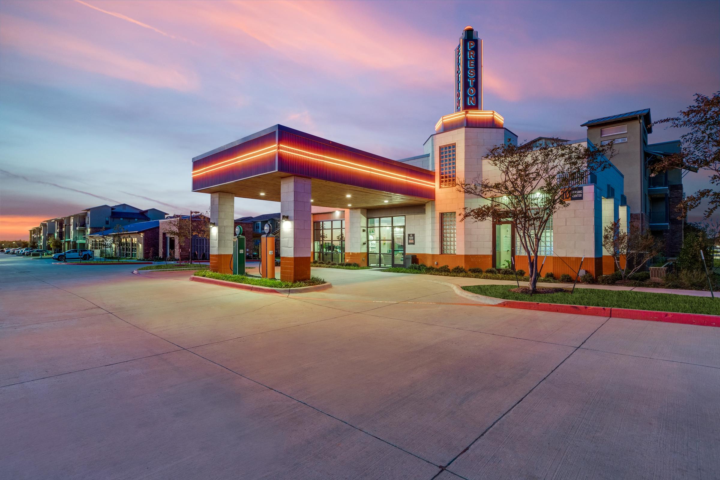 Art deco-inspired commercial retail center with neon signage, porte-cochere entrance, and vibrant pink twilight sky in Celina, Texas