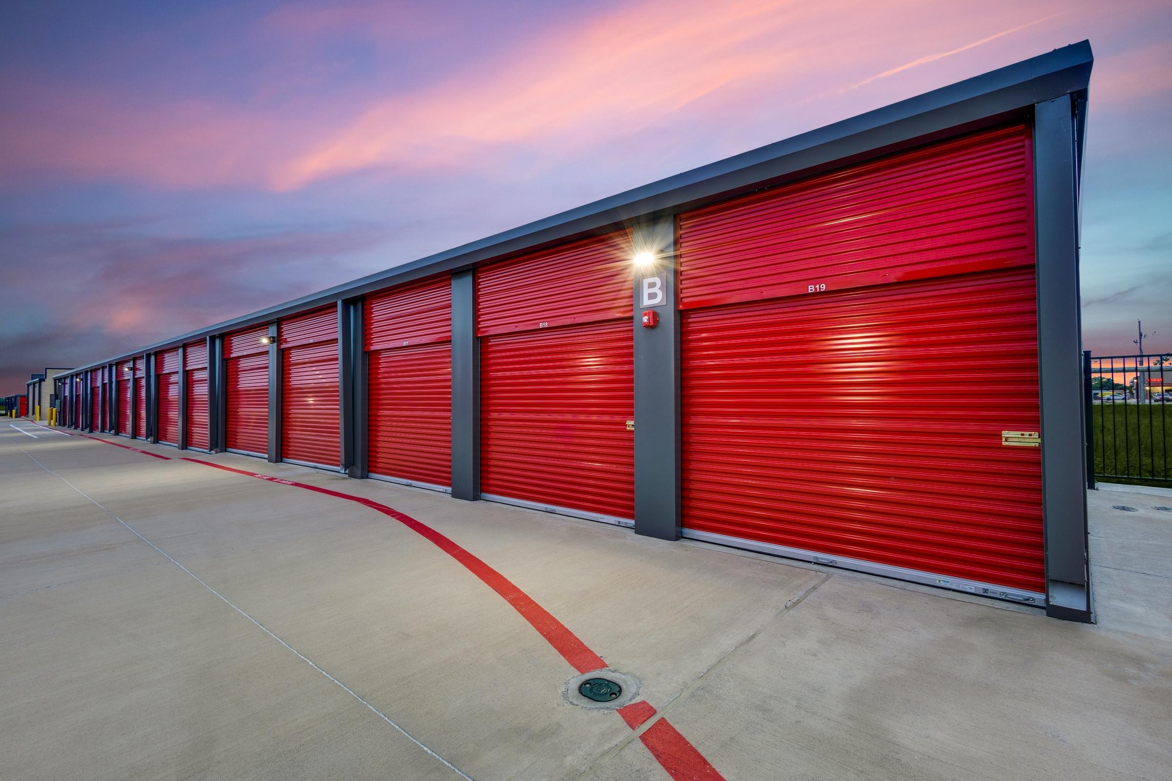 Self-storage facility with red roll-up doors photographed at twilight with dramatic sky in Princeton, Texas