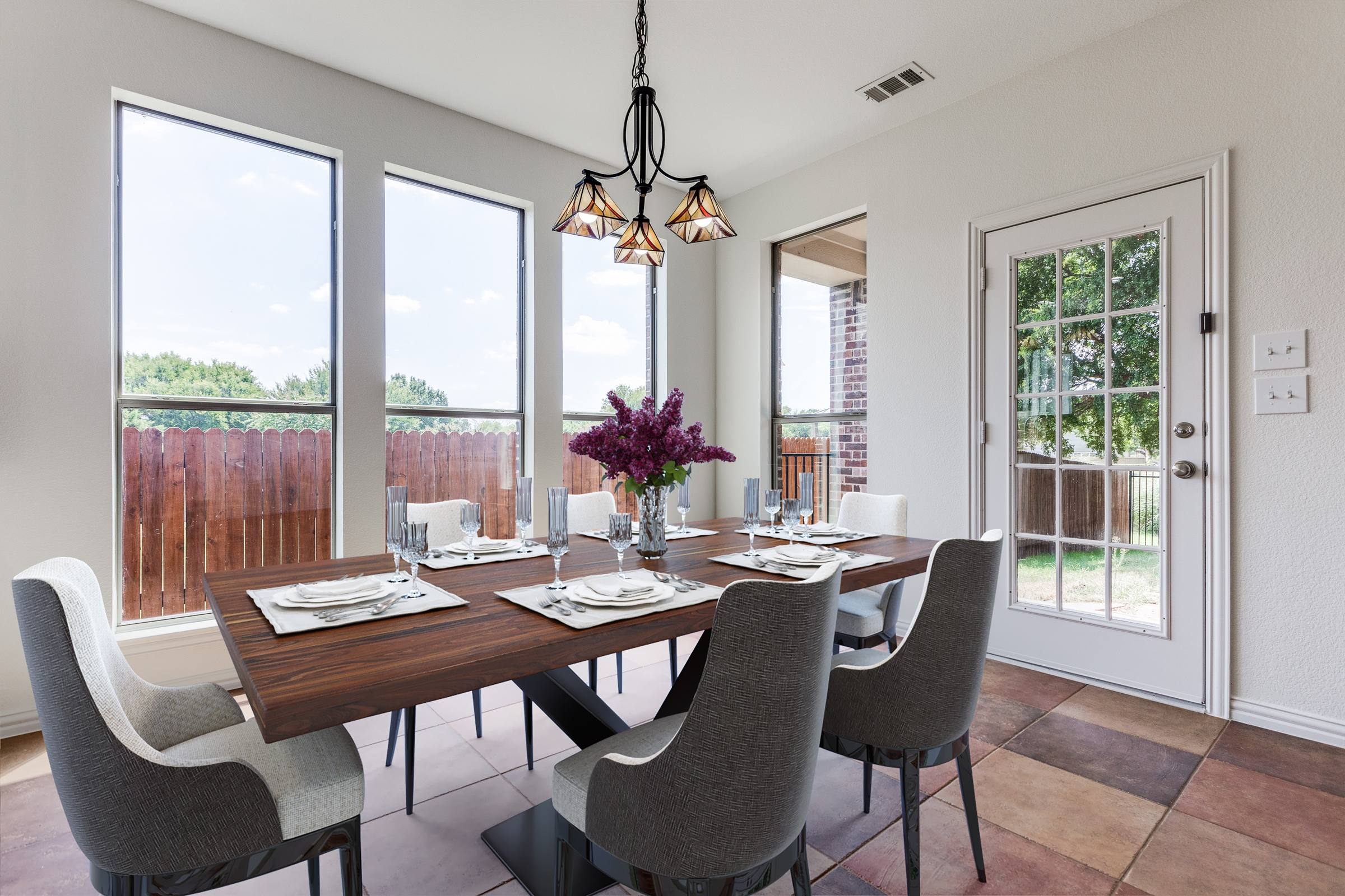 Virtually staged dining room with walnut table for six, upholstered chairs, purple floral centerpiece, and place settings in McKinney, Texas