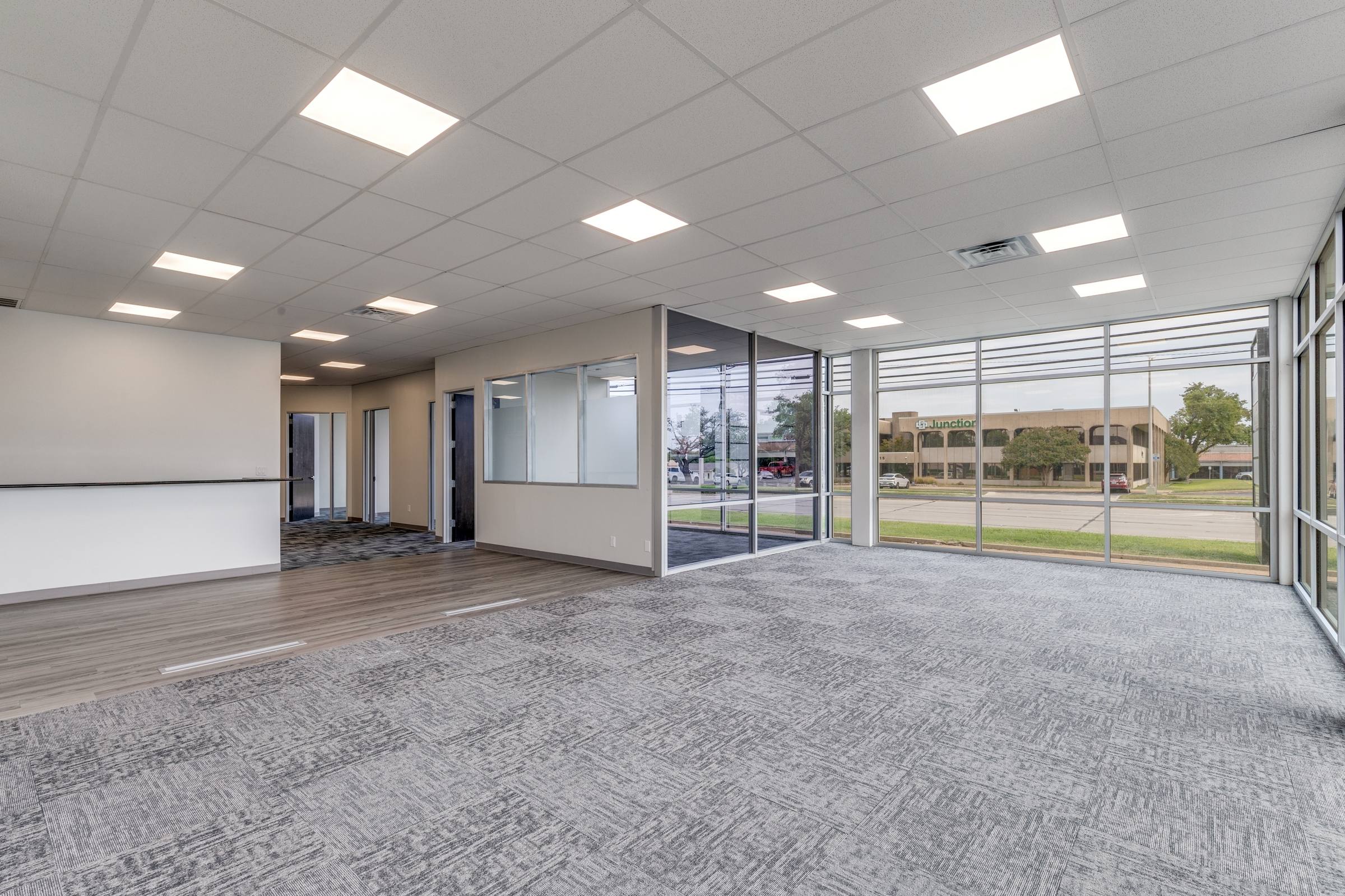 Empty commercial office space with carpet, glass walls, and large windows before virtual staging in Farmers Branch, Texas