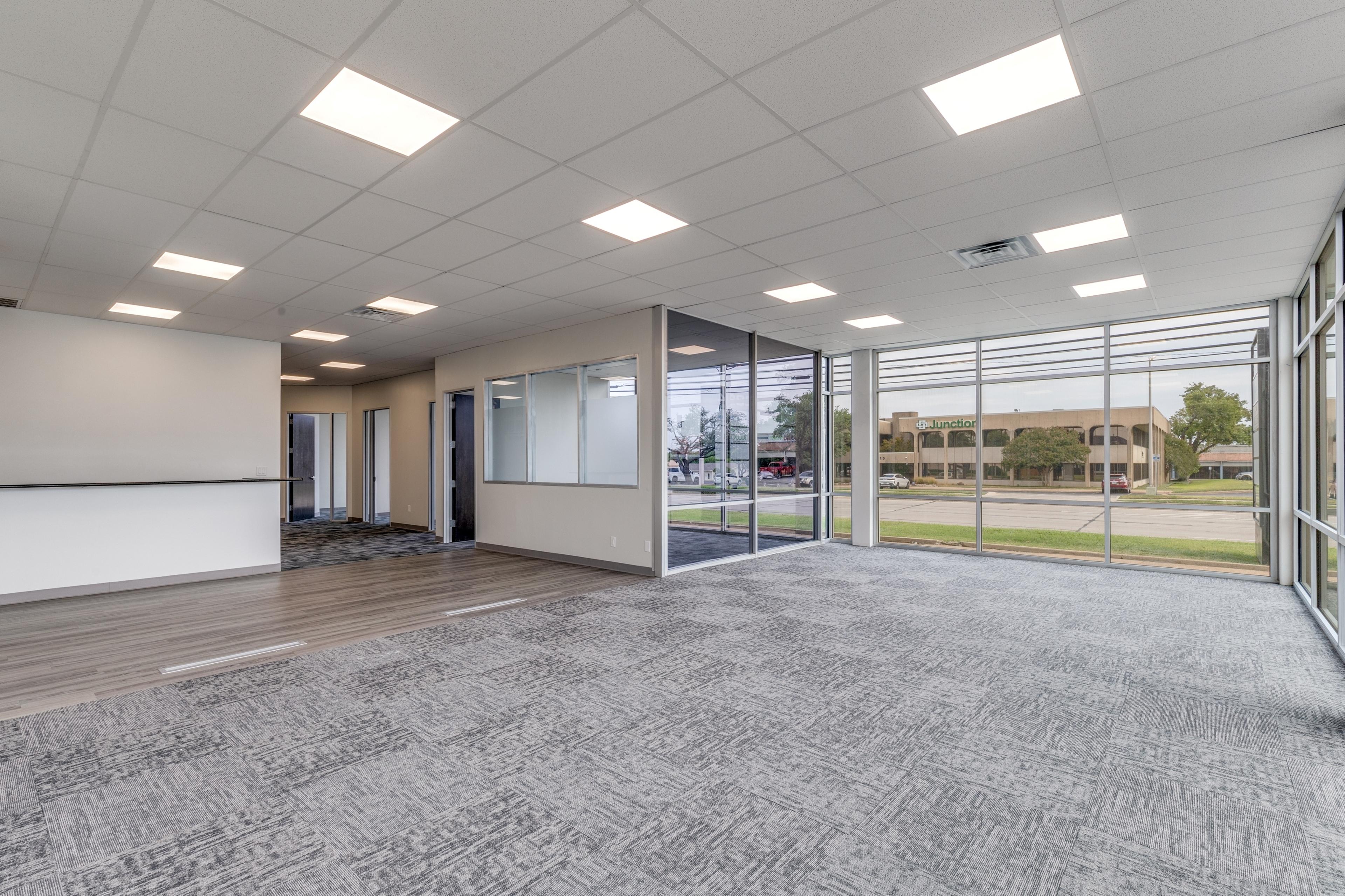 Empty commercial office space with carpet, glass walls, and large windows before virtual staging in Farmers Branch, Texas