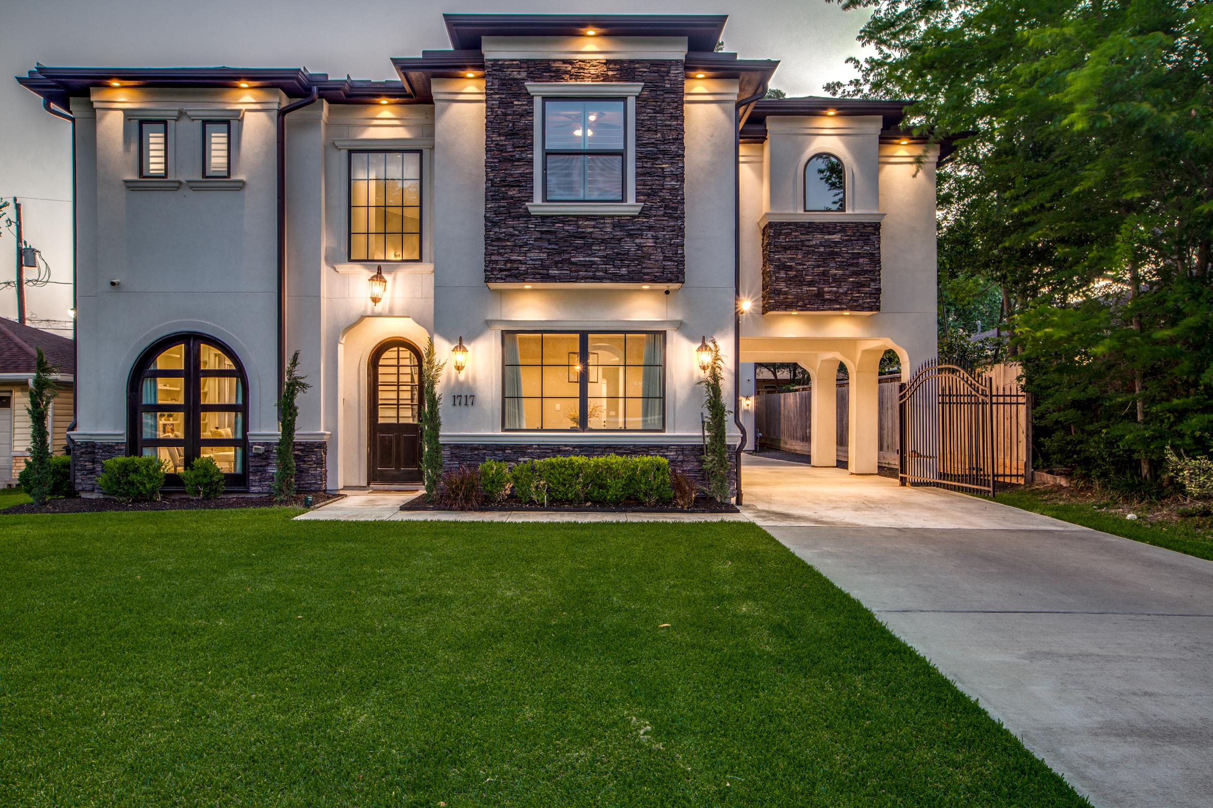 Two-story luxury home exterior at twilight with warm window lighting in Houston, TX