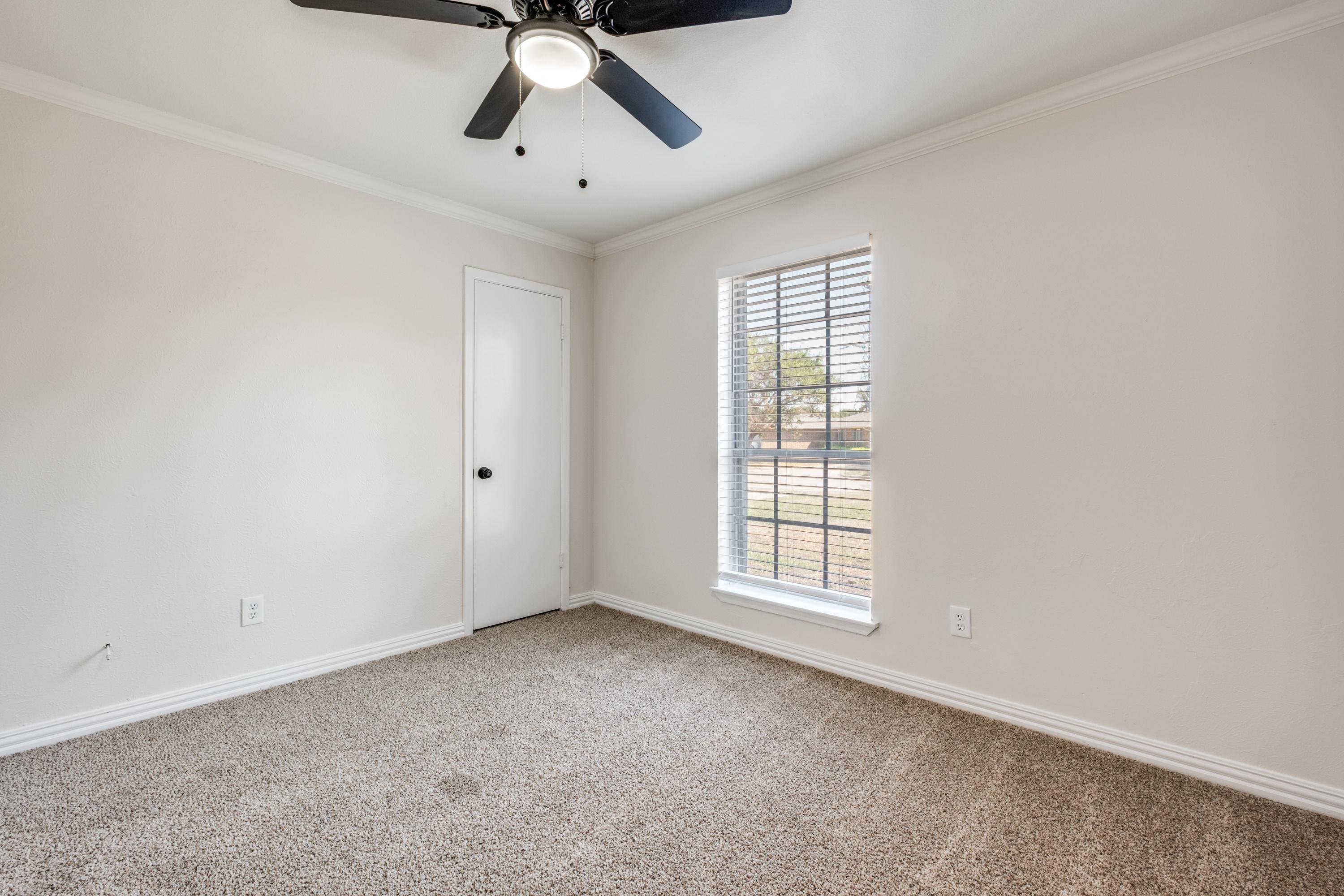 Empty room with carpet, ceiling fan, and window before virtual staging as nursery in Mesquite, Texas