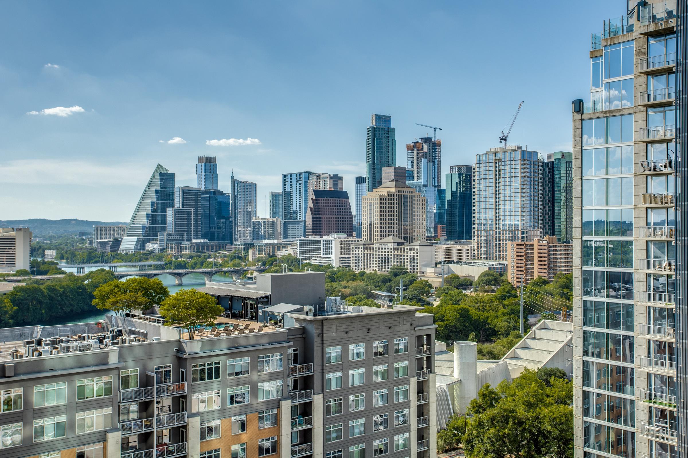 Elevated view from a high-rise apartment overlooking mid-rise buildings, Lady Bird Lake, and the Downtown Austin skyline in Austin, Texas