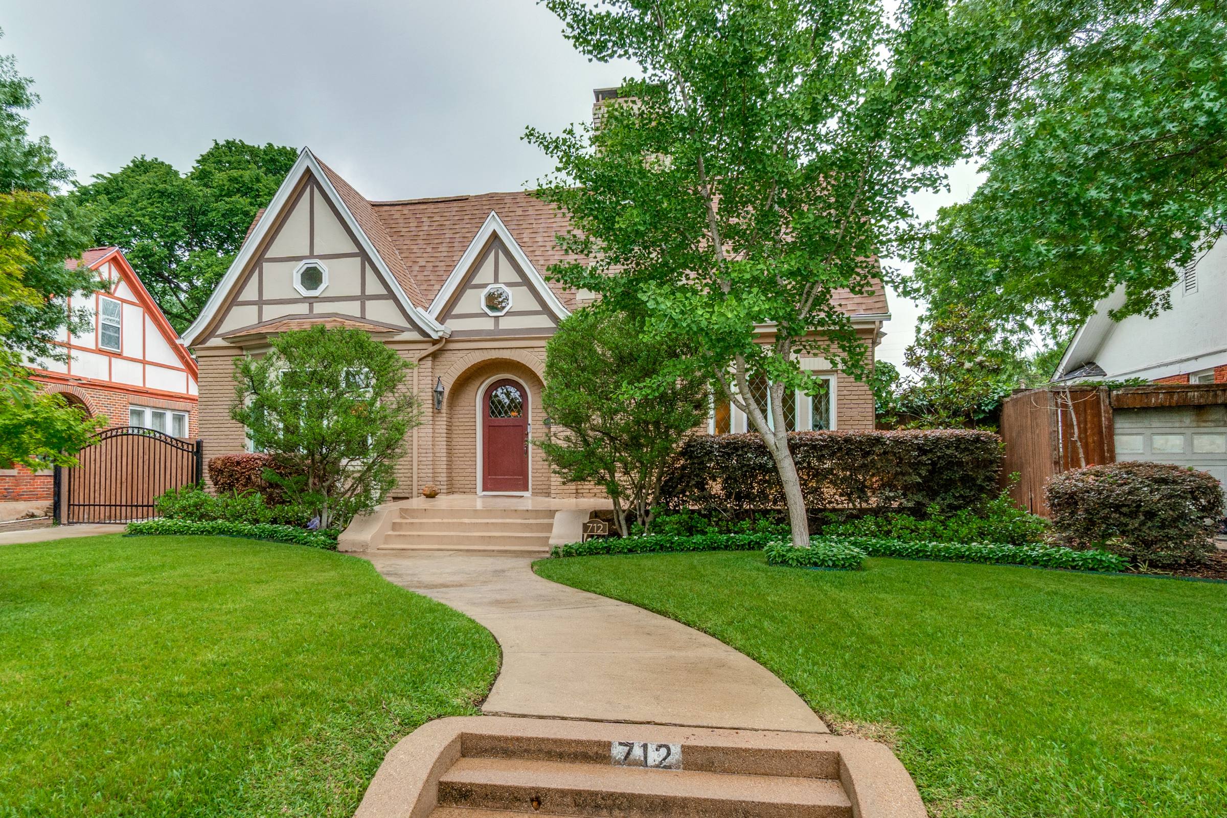 Tudor-style home front exterior in Dallas with overcast gray sky before blue skies photo enhancement