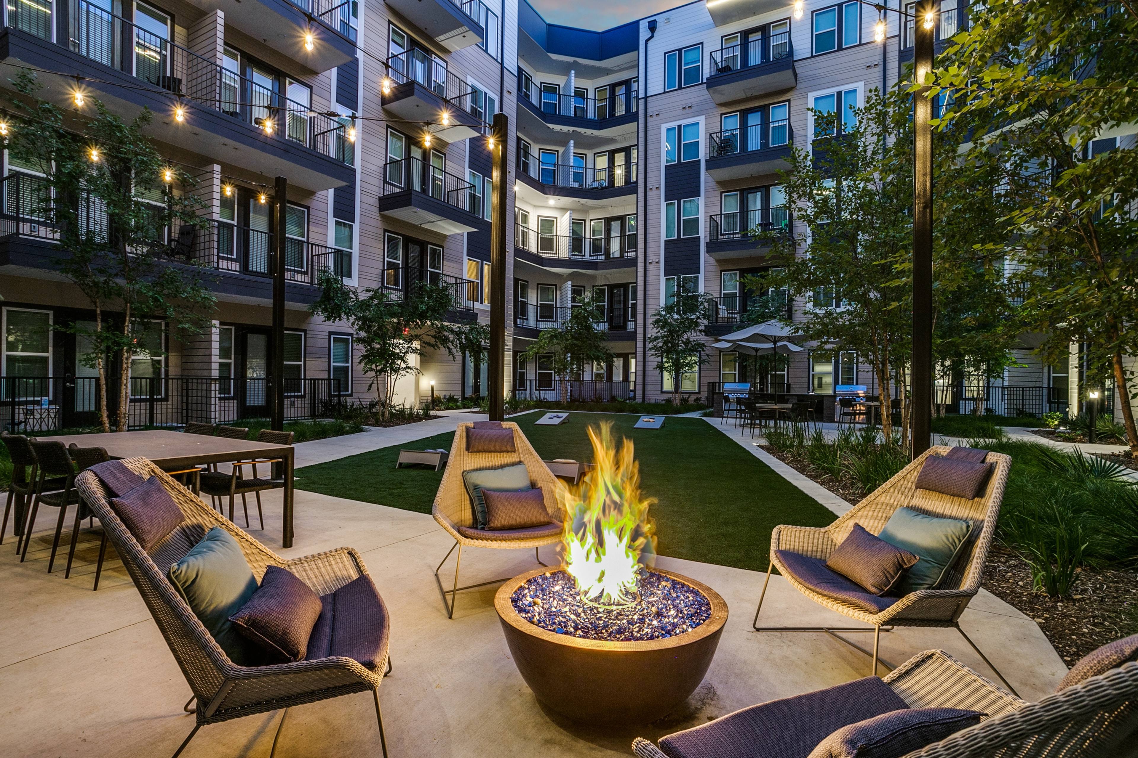 Twilight courtyard with fire pit and string lights at a luxury apartment community in Dallas, Texas