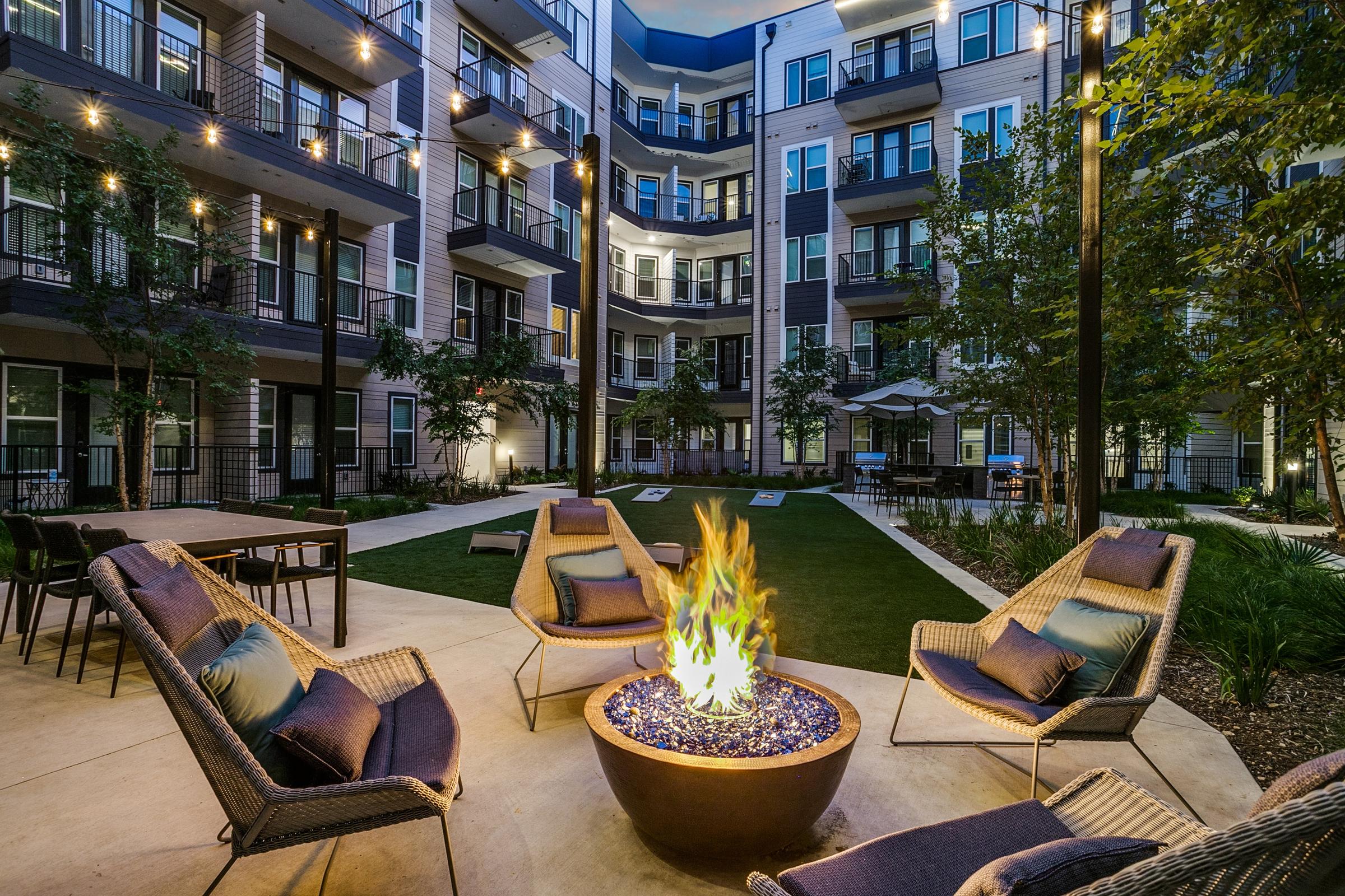 Twilight courtyard with fire pit and string lights at a luxury apartment community in Dallas, Texas