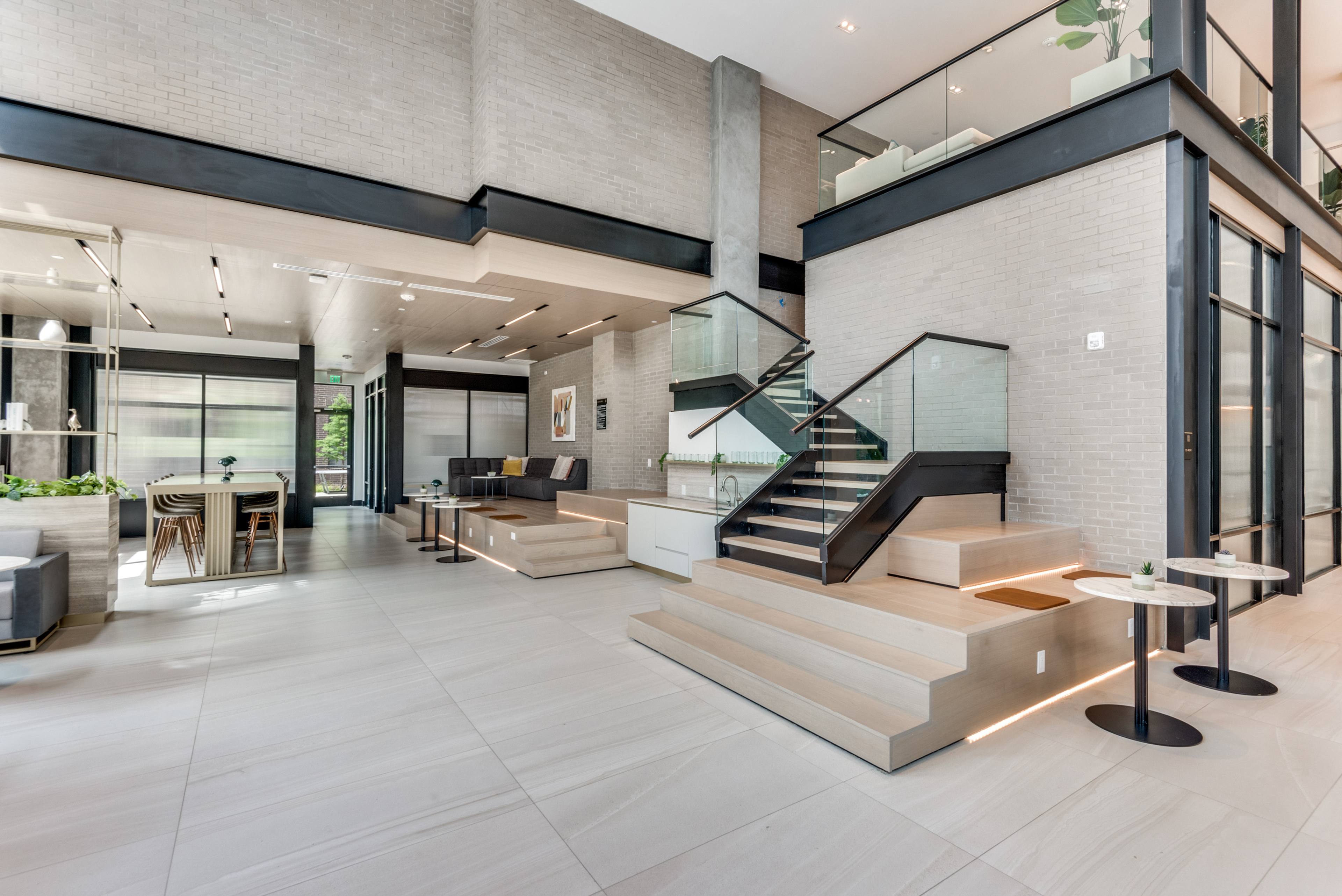 Modern multi-level commercial lobby with a floating staircase, glass railings, and lounge seating in Dallas