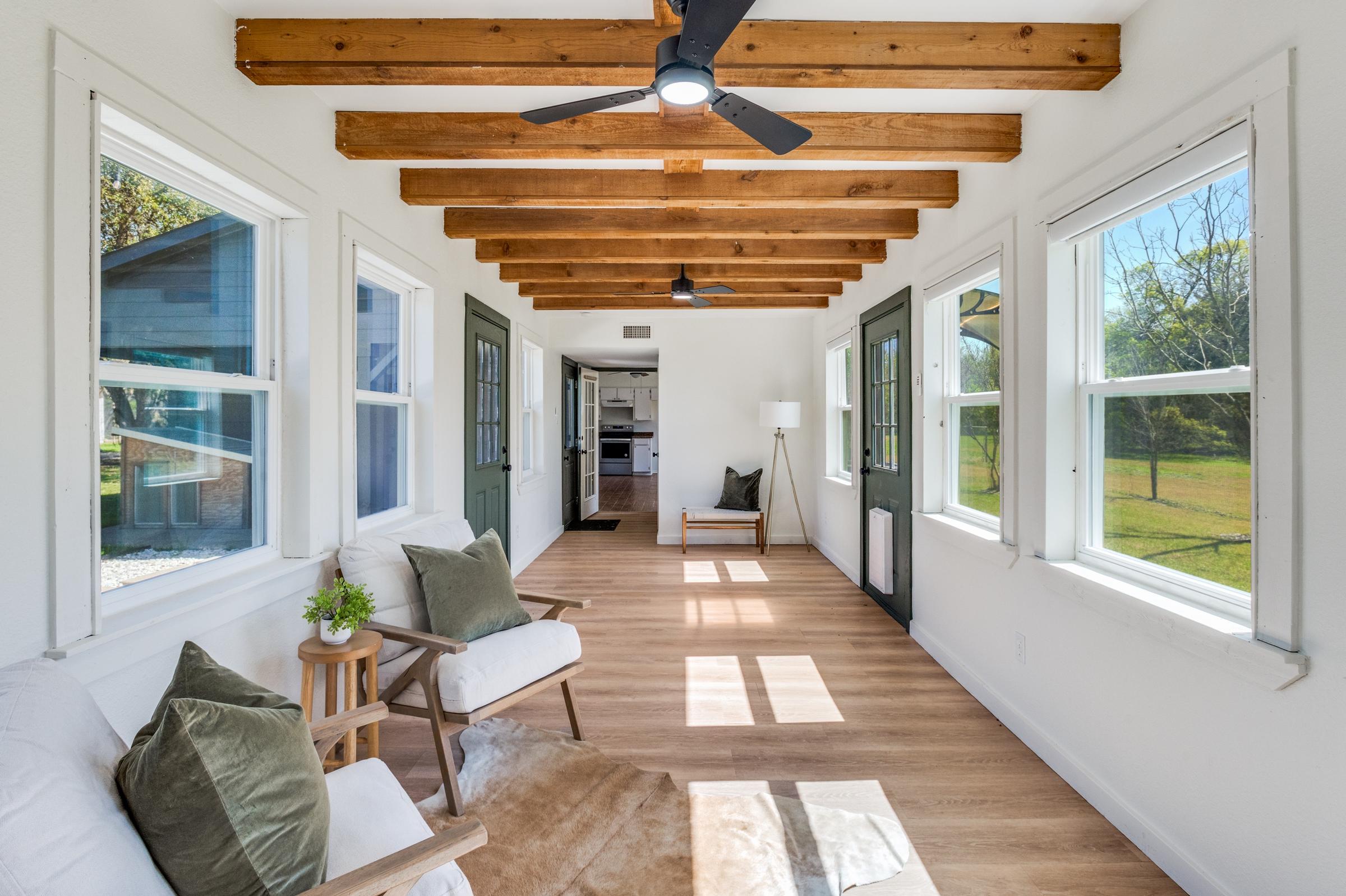 Bright sunroom with exposed wood rafters, hardwood floors, and natural light in a custom home in Seagoville, Texas