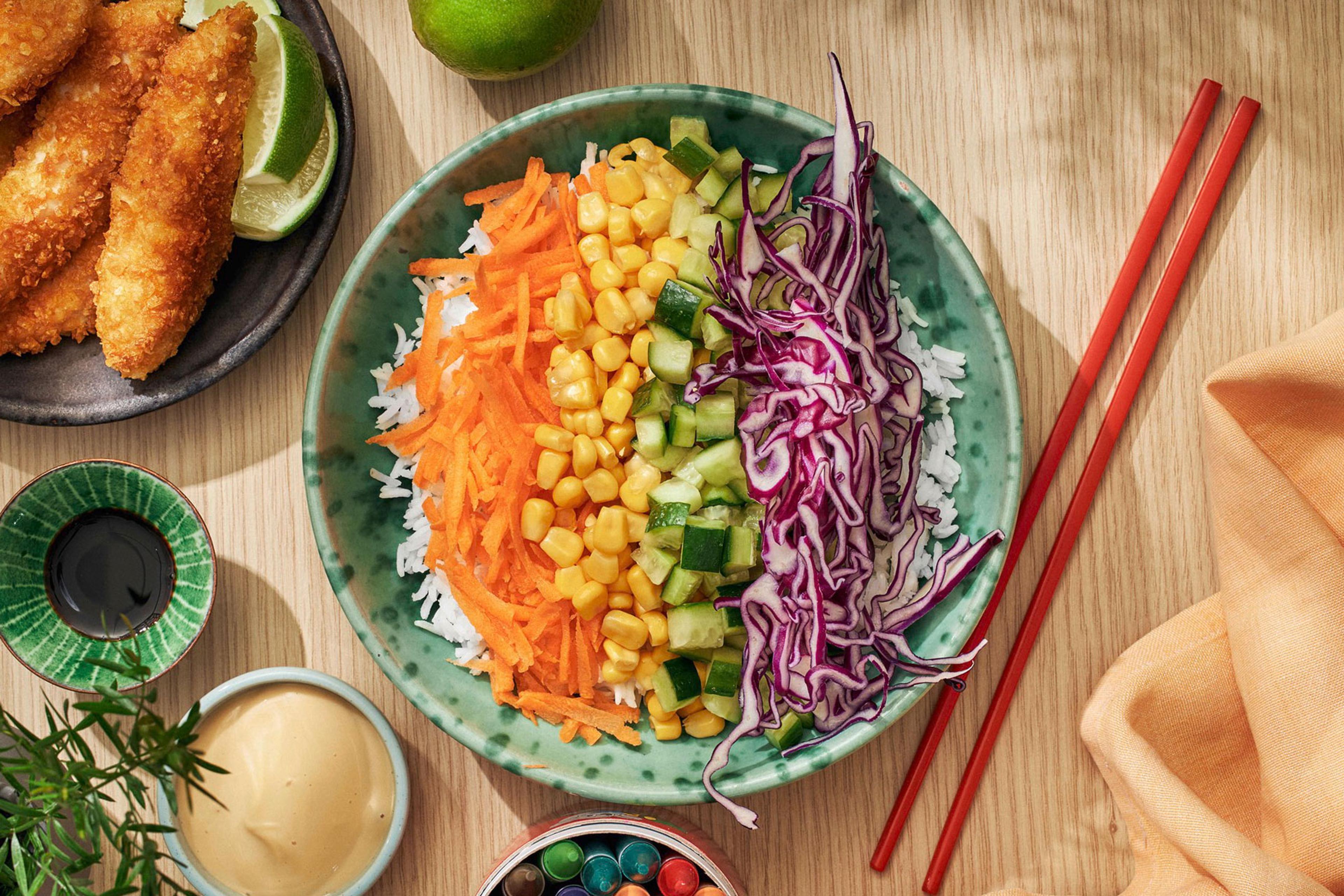 Bowl toppad med grönsaker i olika färger: rödkål, gurka, morot och majs