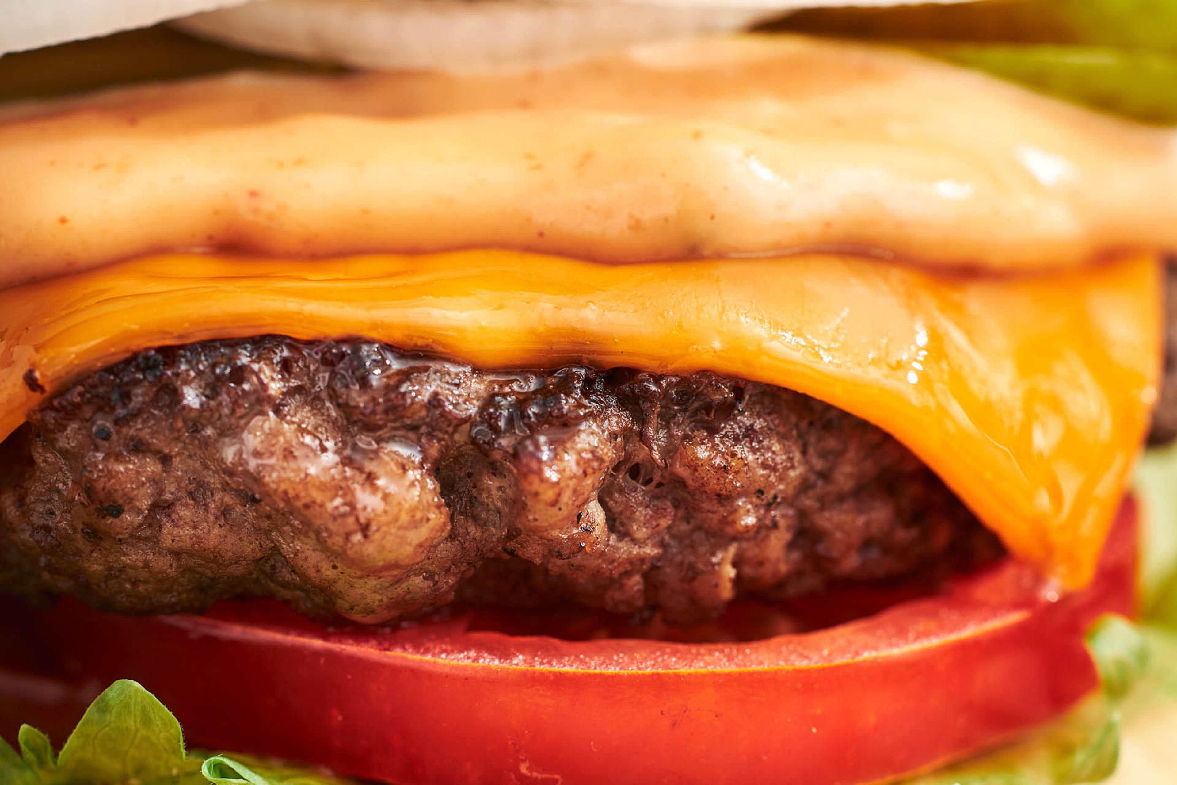 En närbild på Jureskogs American burger med nötfärsburgare, tomat, cheddar, silverlök och hamburgerdressing.