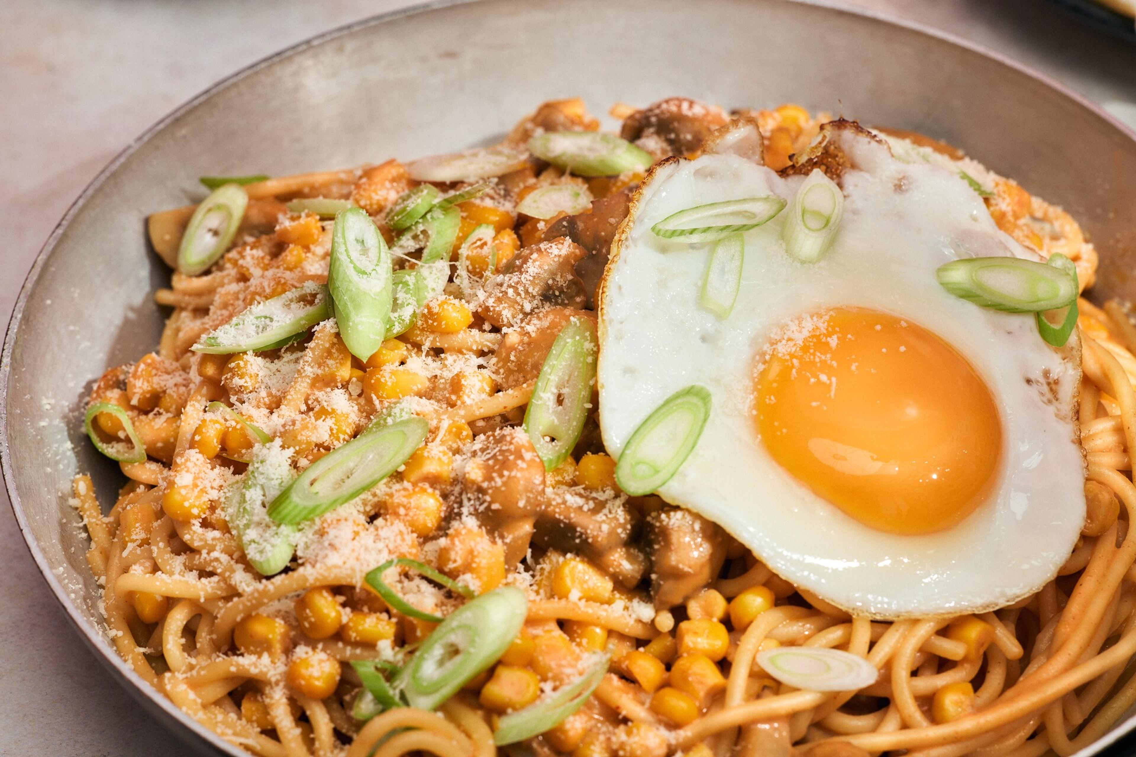 Spaghetti med gochujang, stekt ägg och salladslök i en djup tallrik