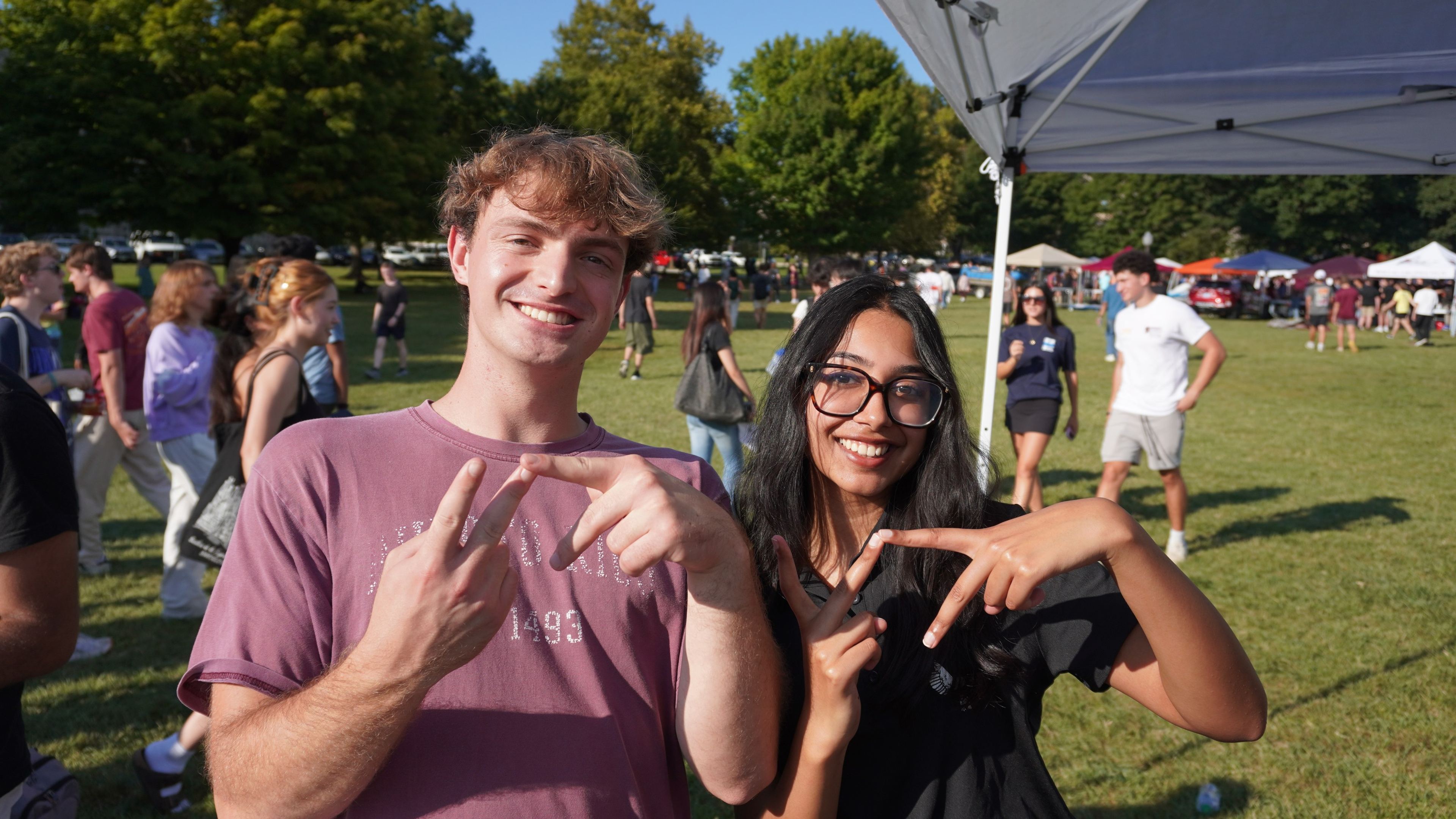 Two people making the VT hand sign at the fair