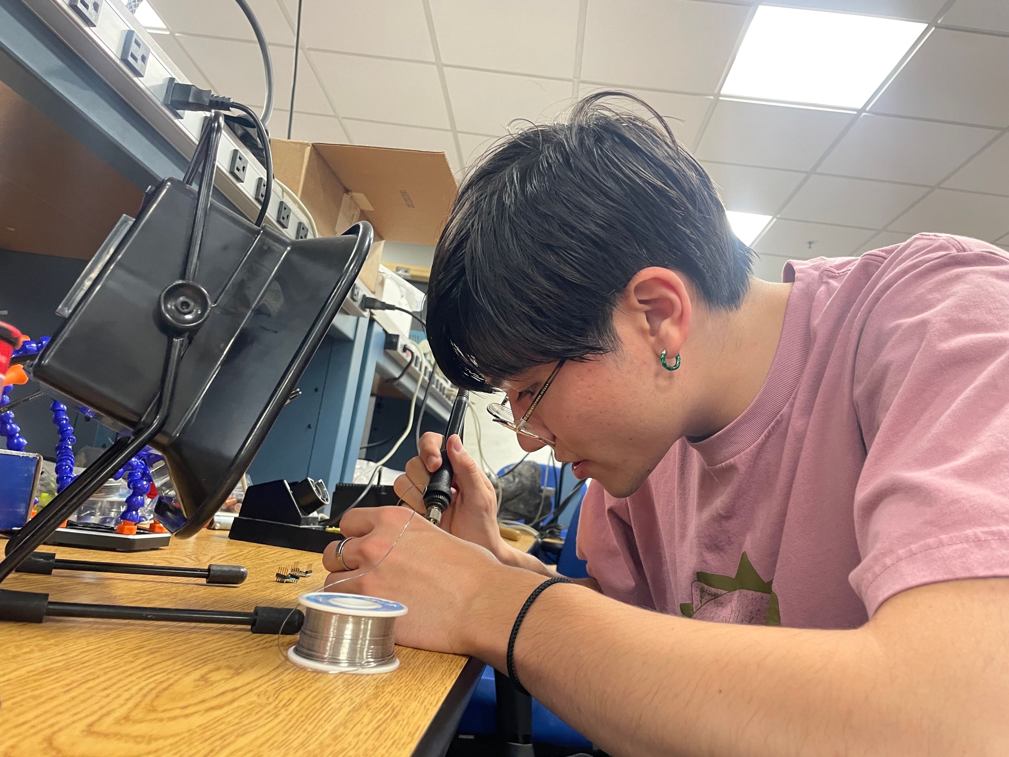 A member soldering at a lab bench