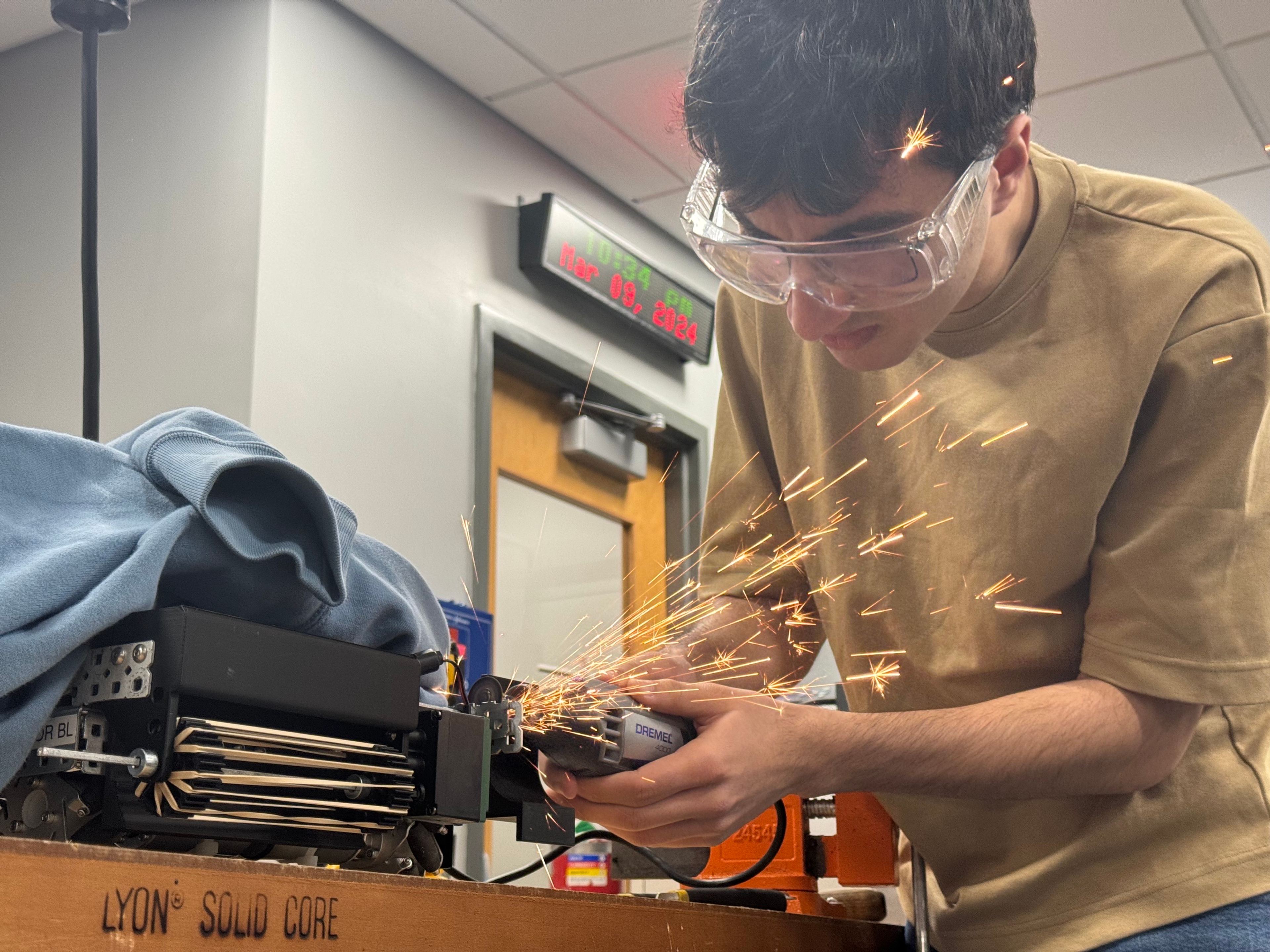 A member cutting metal with a Dremel as sparks fly