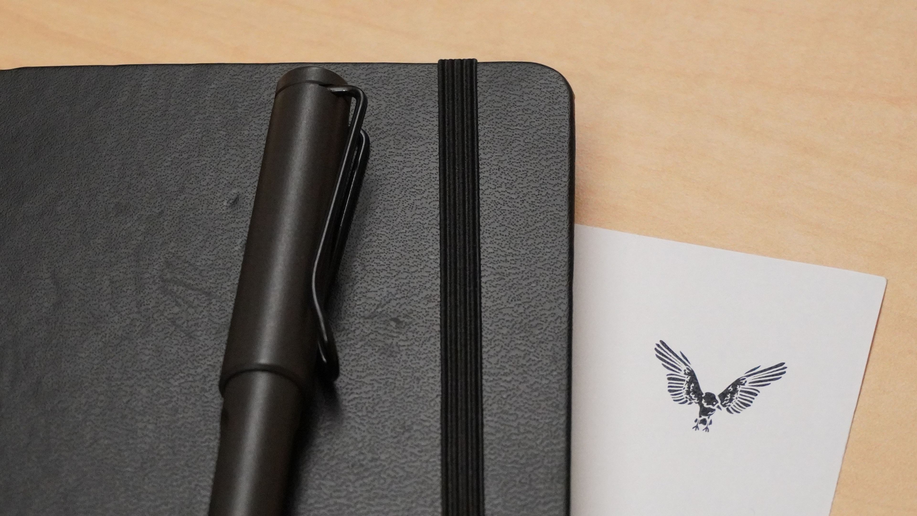 A notebook and pen beside a card with the VT CRO bird