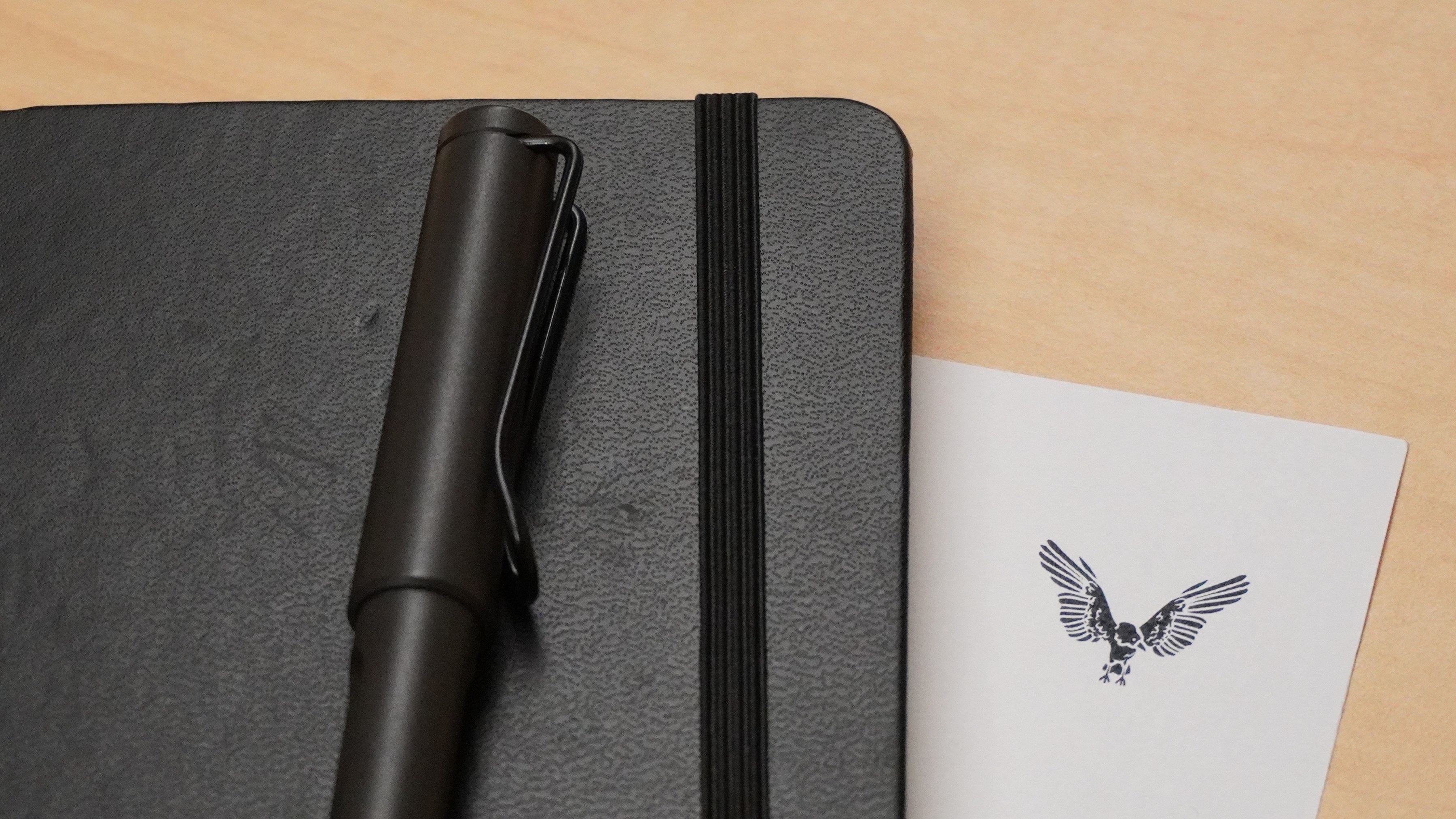 A notebook and pen beside a card with the VT CRO bird