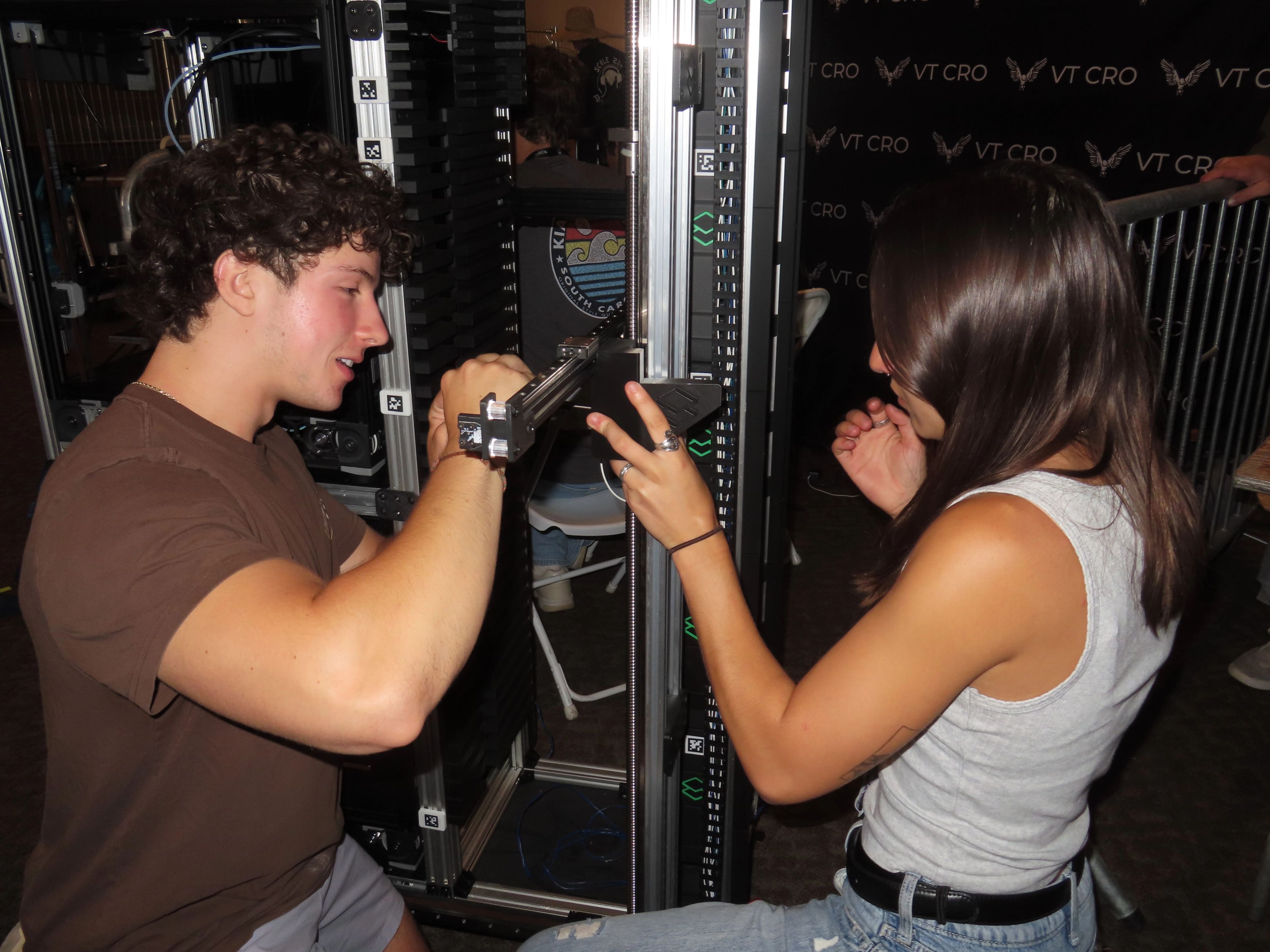Two members working on a machine at the VT CRO booth