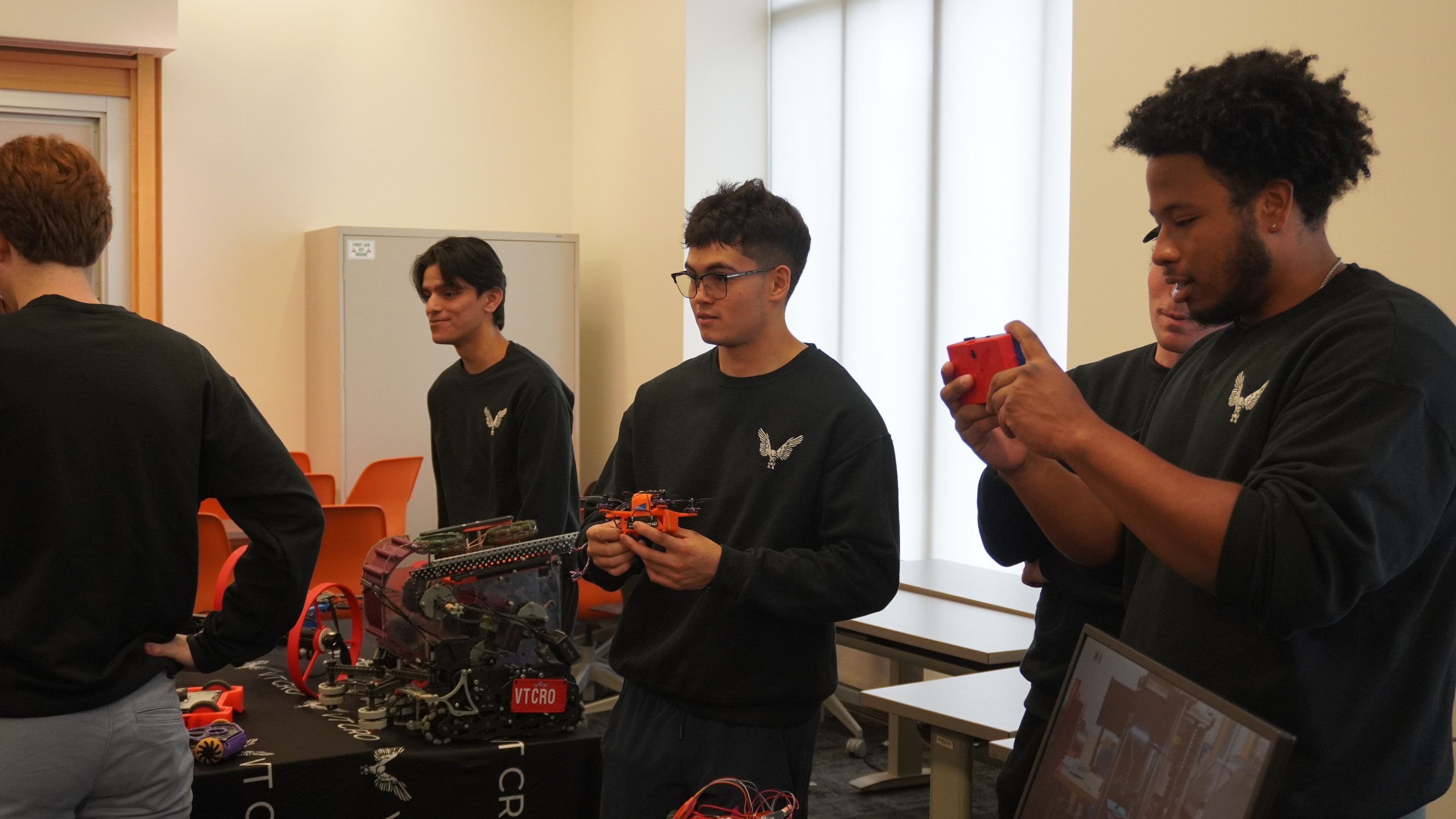 Members in VT CRO shirts showing their robots and a drone