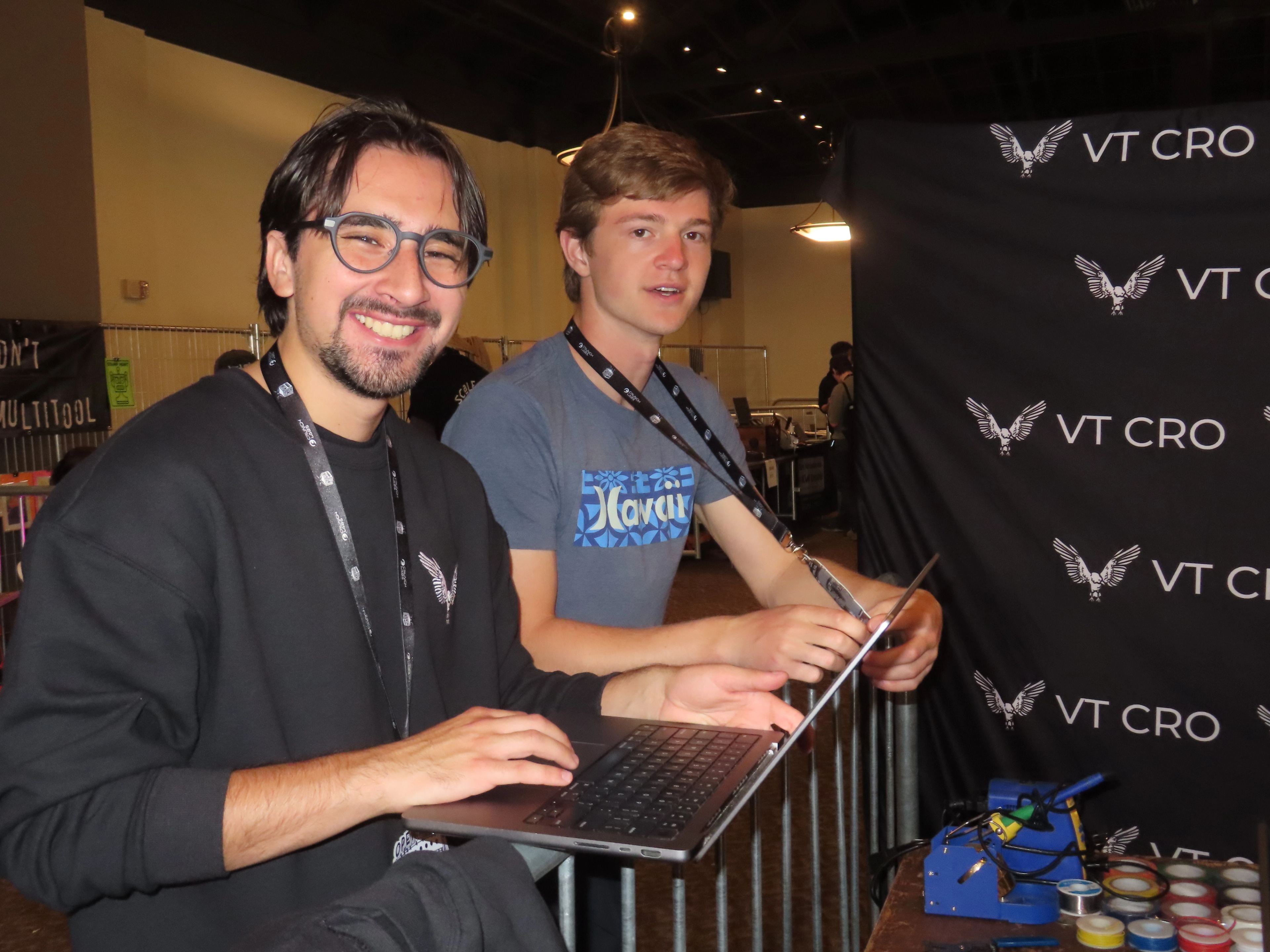 Two members at a laptop in front of the VT CRO backdrop