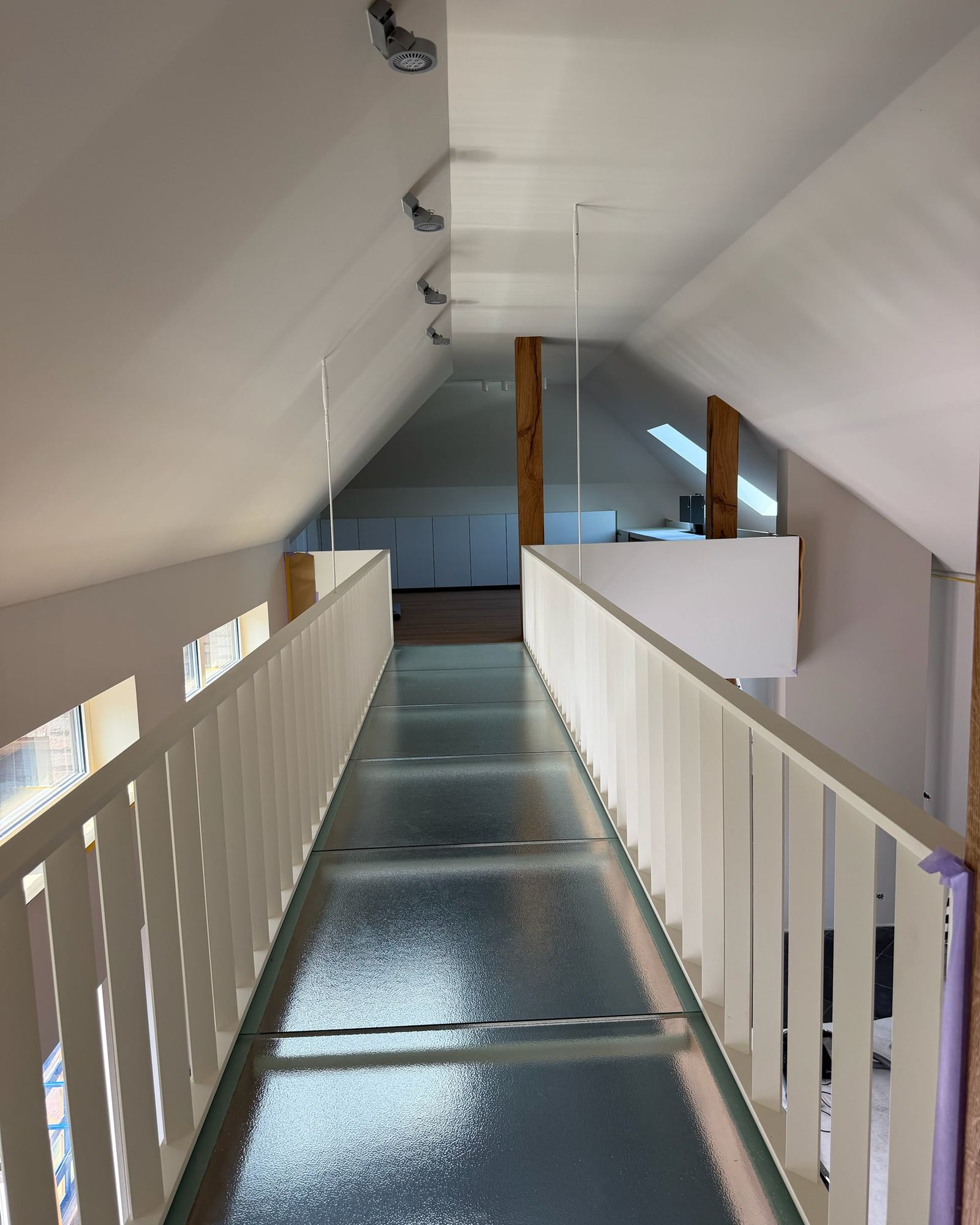 Loopbrug met vloer van structuurglas tussen witte spijlenbalustrades, met eiken staanders onder de schuine kap