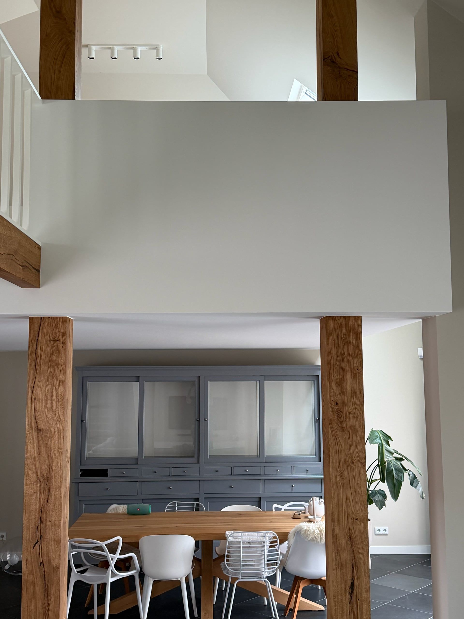 Vide met witte borstwering en eiken staanders boven de eethoek, met een witte spijlenbalustrade op een eiken balk