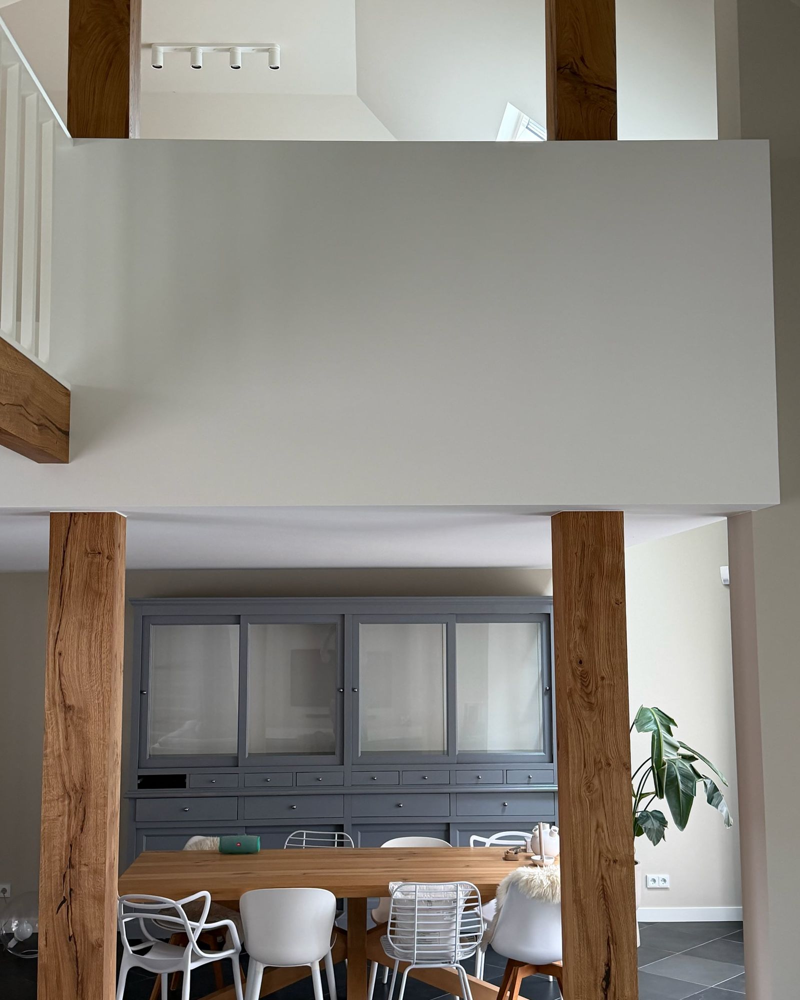 Vide met witte borstwering en eiken staanders boven de eethoek, met een witte spijlenbalustrade op een eiken balk