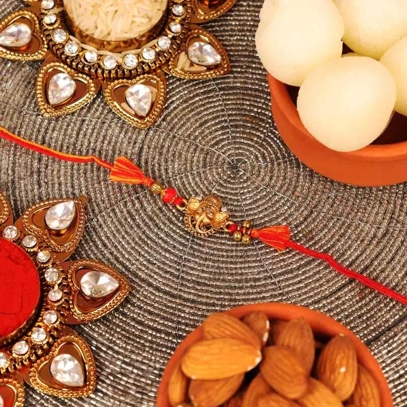 ganesha-rakhi-with-tin-rasgulla-and-almonds_1.webp