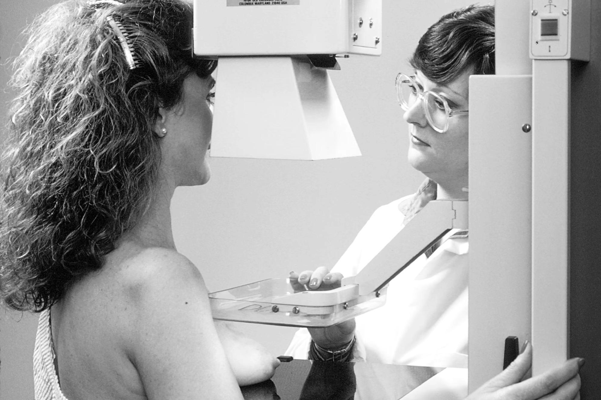 Woman receiving a mammogram from a technologist, showing breast cancer screening and mammogram radiation safety.