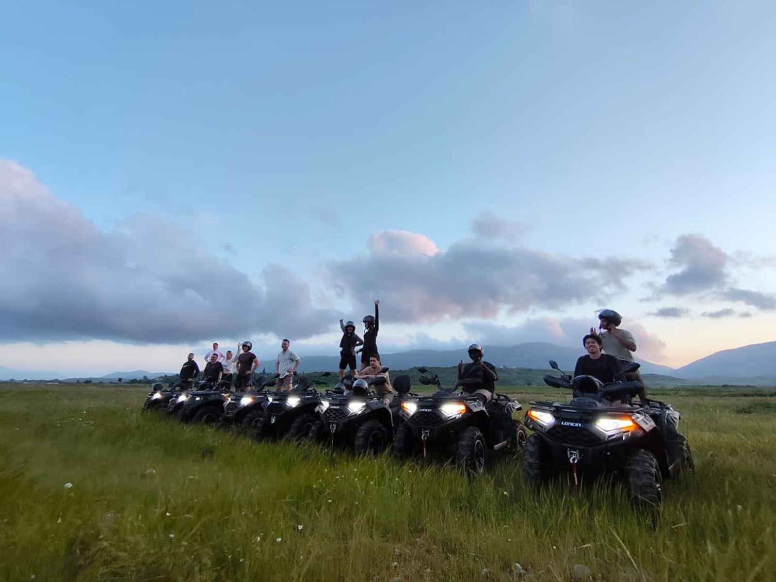 A group of riders on quad bikes at golden hour in the hills above Saranda