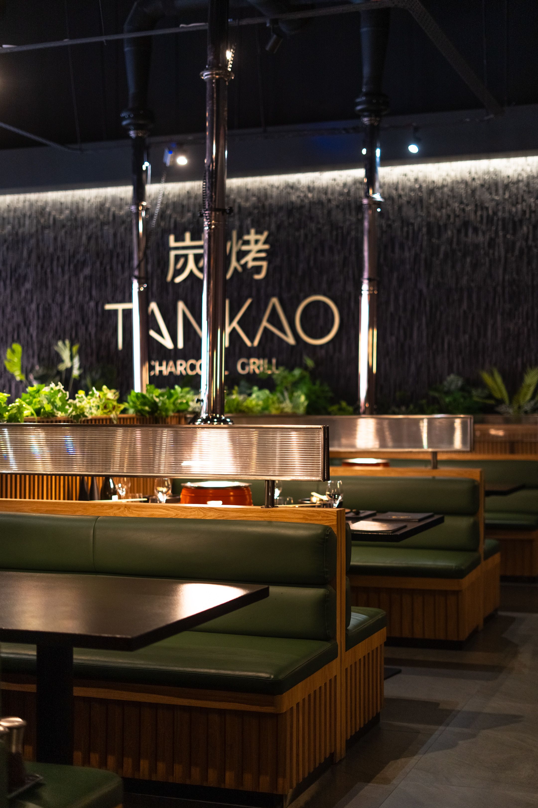 Main dining area of Tankao Restaurant featuring charcoal grill-focused interior with industrial finishes and warm lighting.