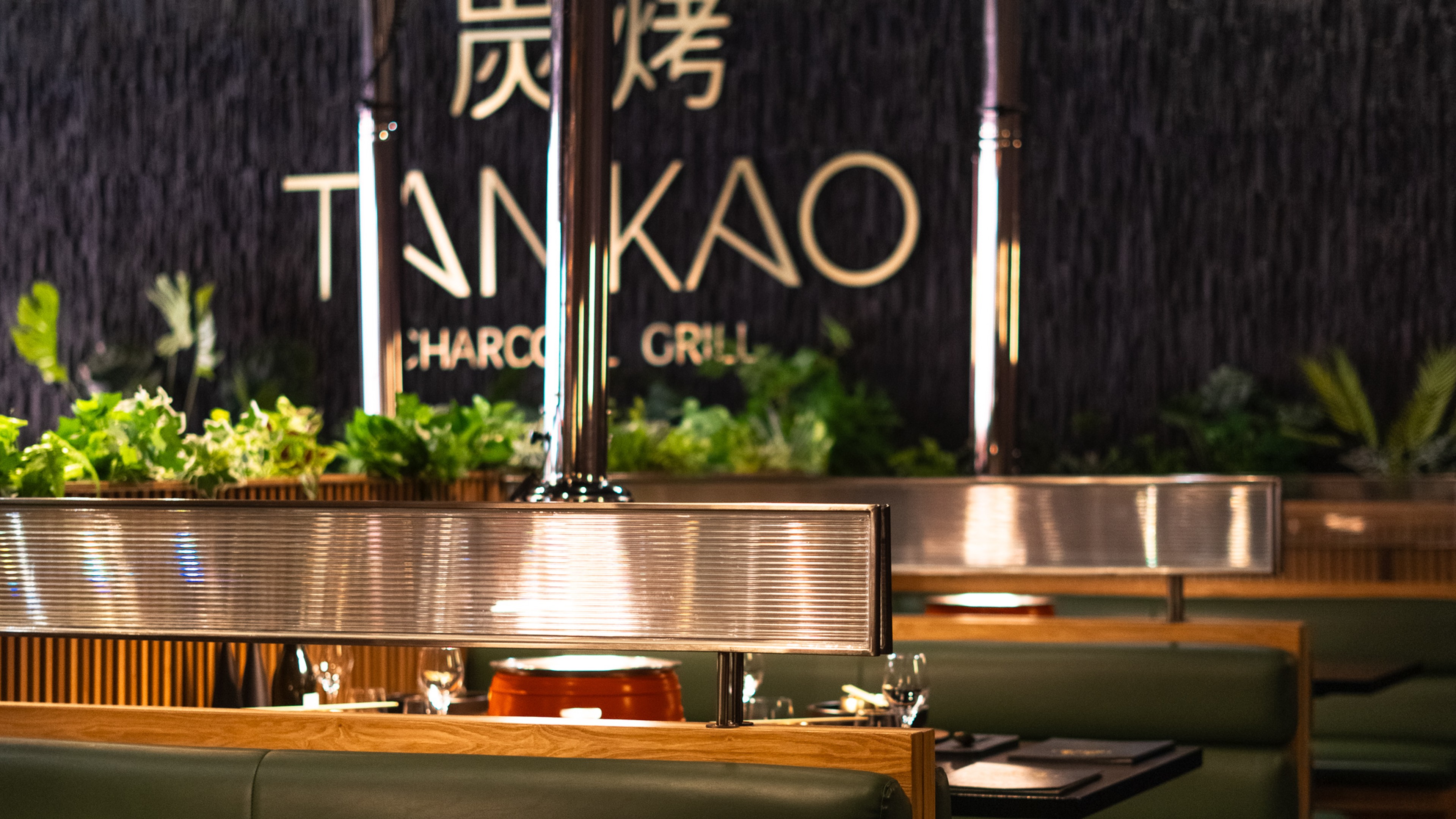 Main dining area of Tankao Restaurant featuring charcoal grill-focused interior with industrial finishes and warm lighting.