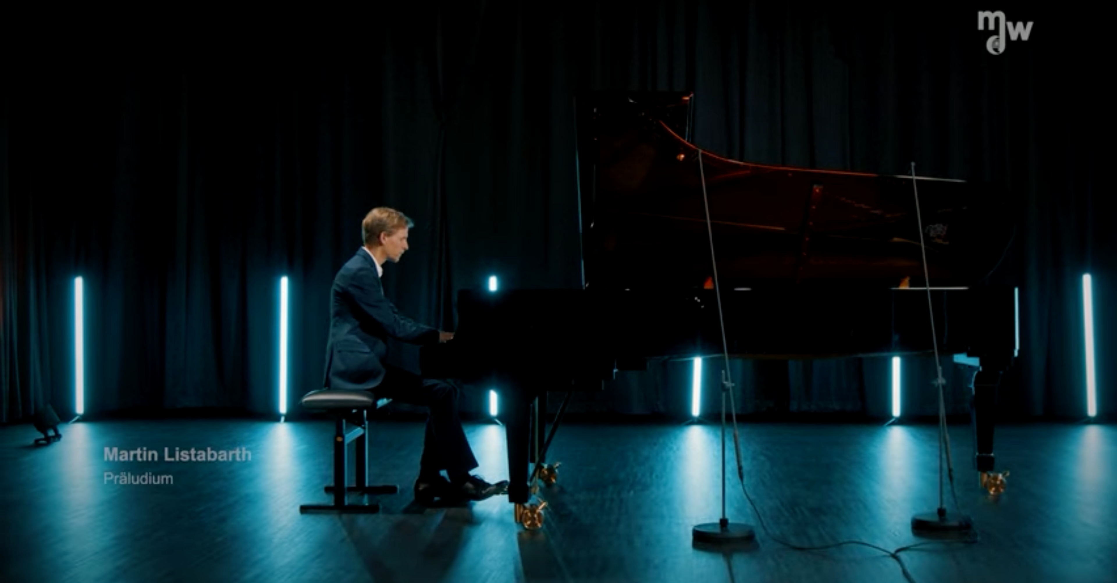 Martin Listabarth spielt am Klavier in einem dunklen, mit bläulichen Scheinwerfern beleuchteten, Tonstudio.