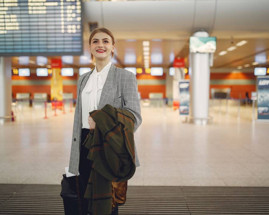 A traveller with luggage standing by an airport departure board