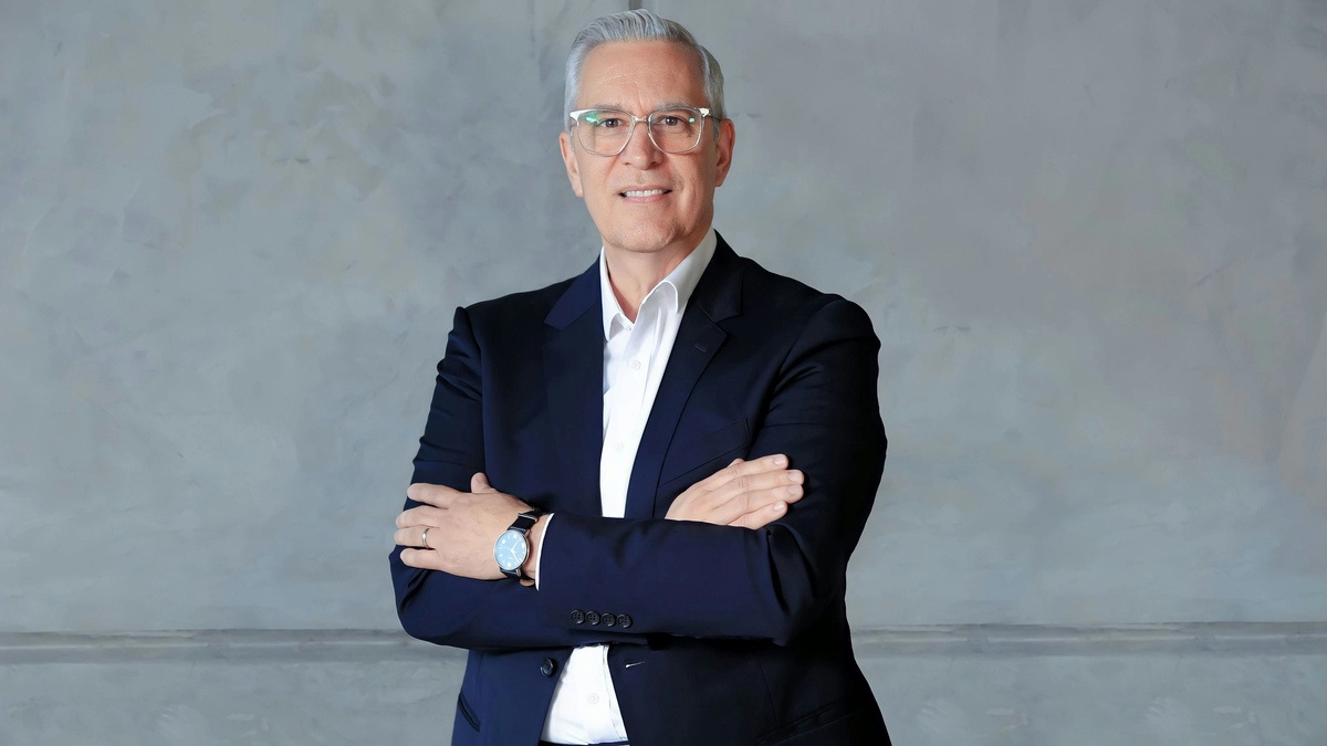 a corporate headshot of a white man in formal suit with gray background