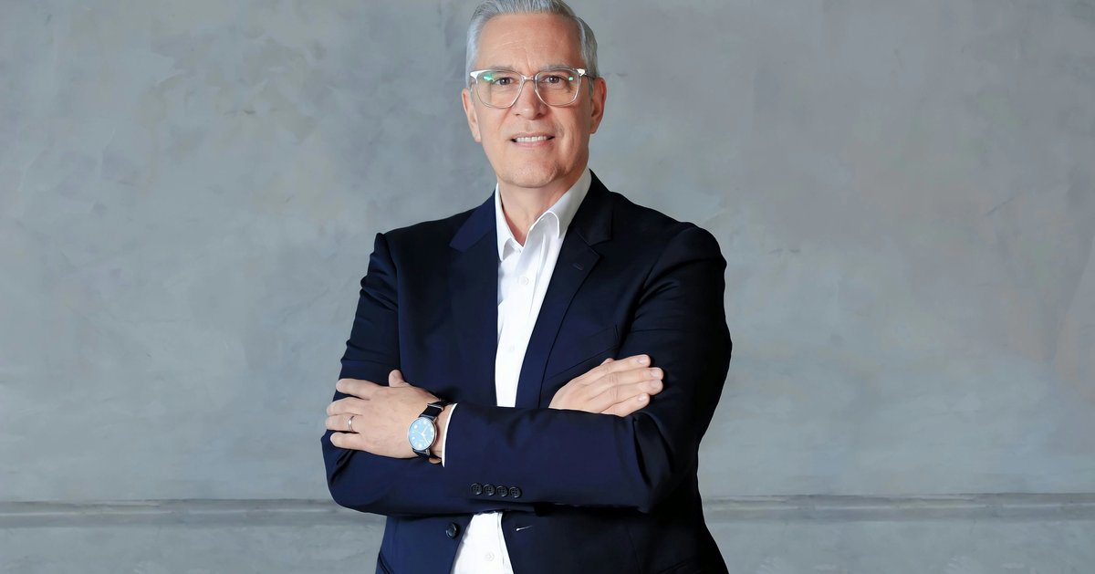 a corporate headshot of a white man in formal suit with gray background