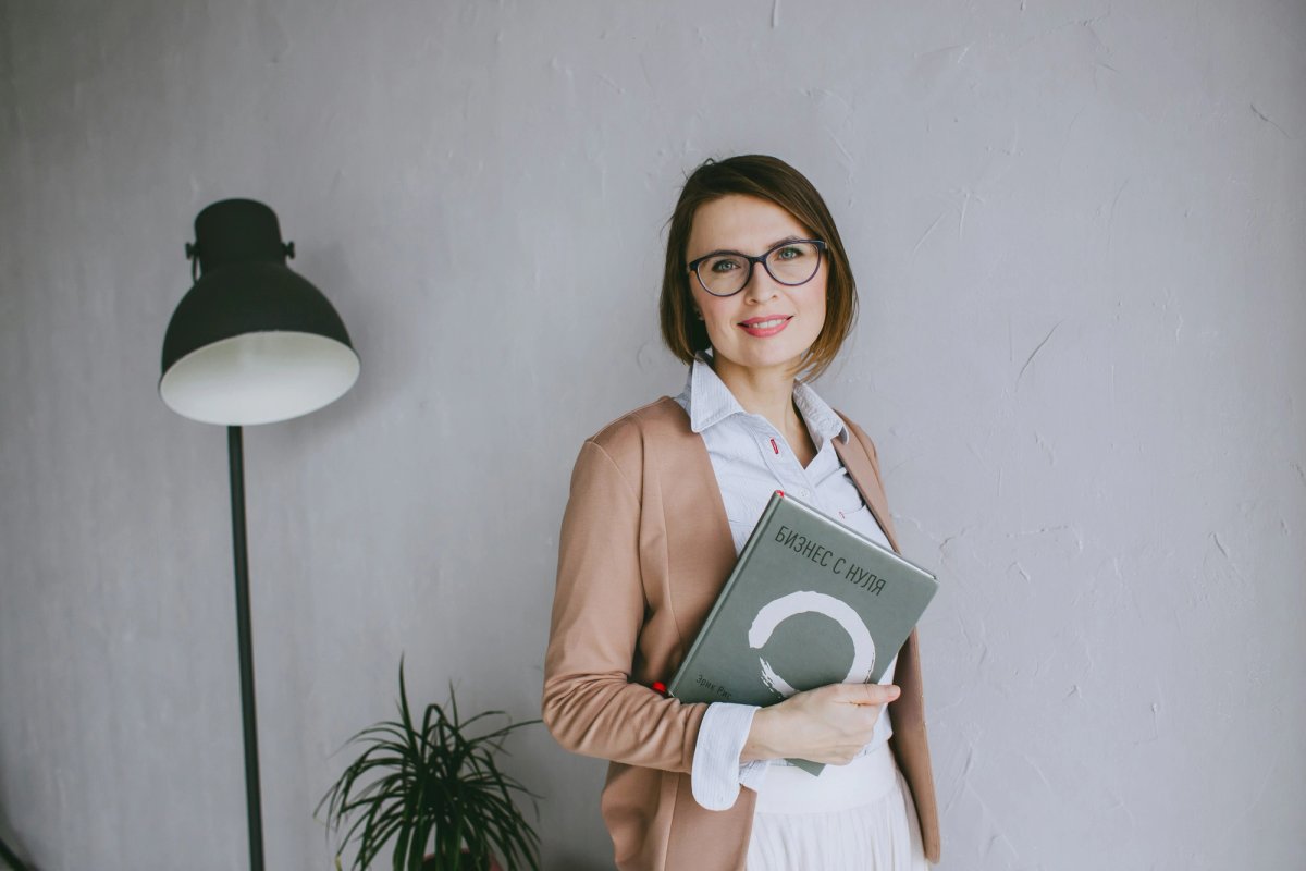 a photo of a woman holding a book against a white wall