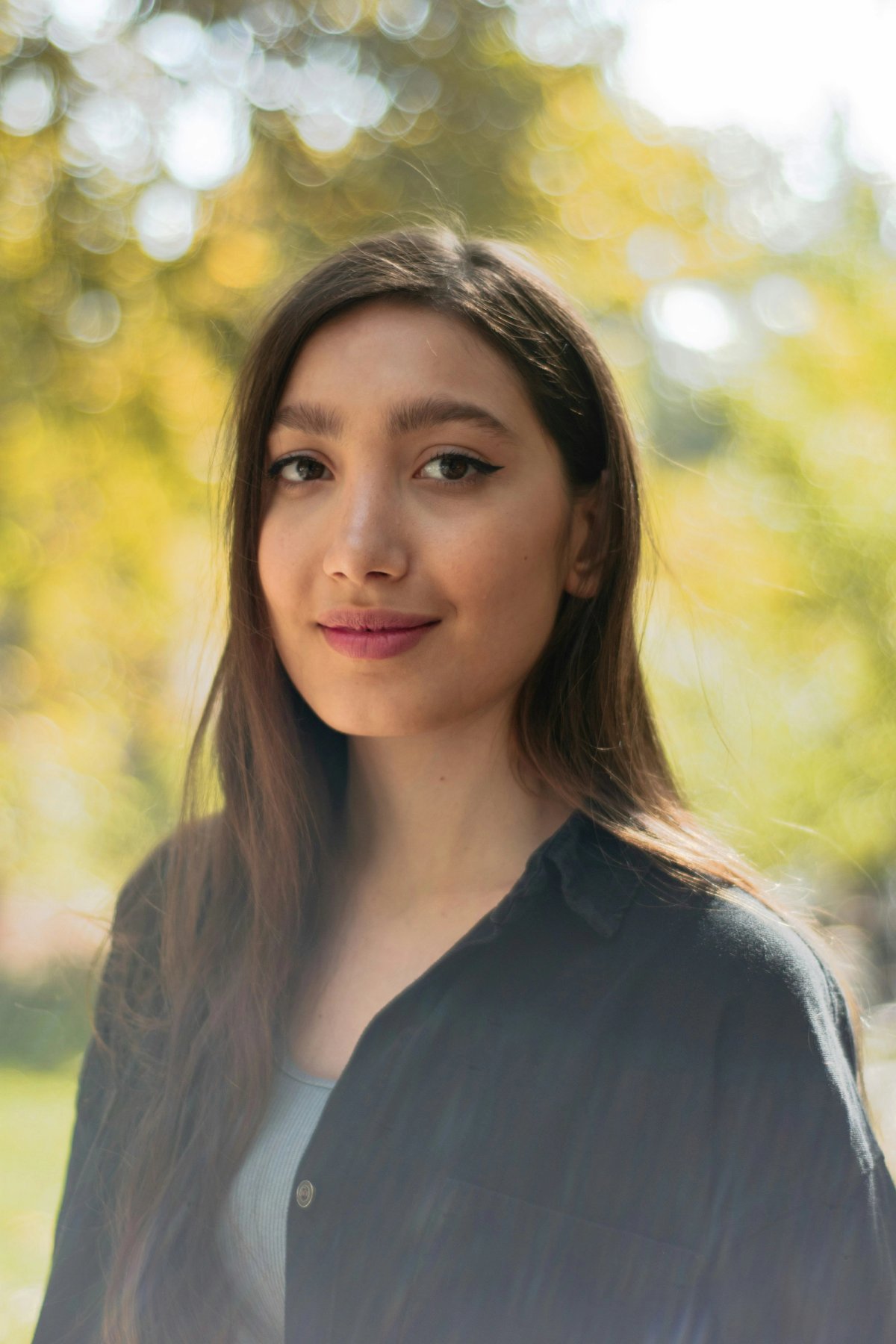 a woman standing in sunlit greenery park