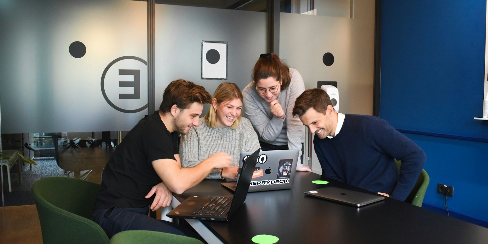 A team of marketers working at laptops in a shared office, comparing Amazon PPC agencies