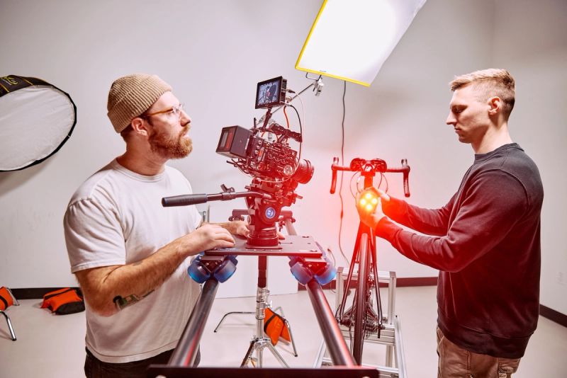 Two crew members lining up a cinema camera on a slider for a bicycle product shoot